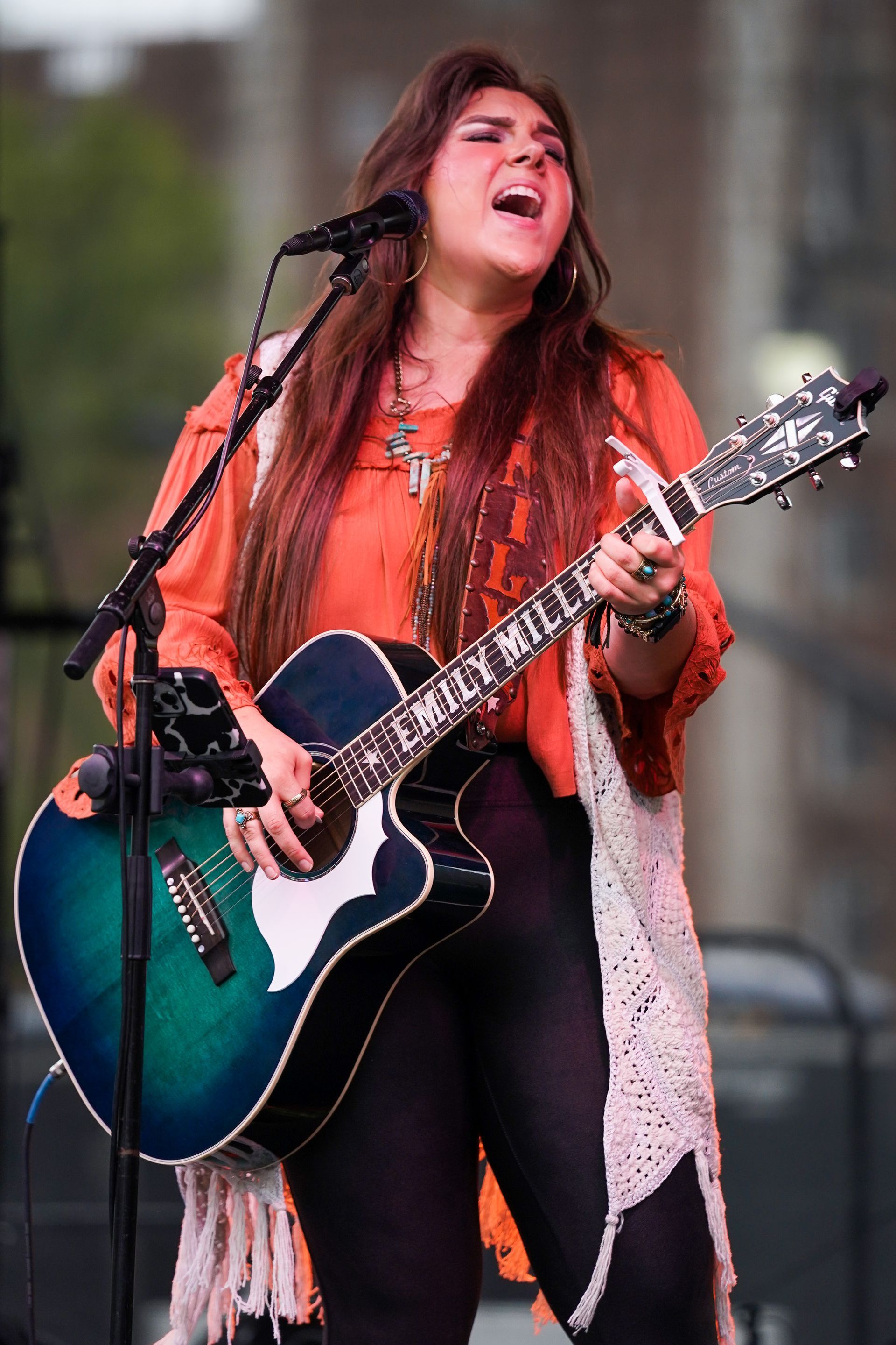 a woman is singing into a microphone while holding a guitar
