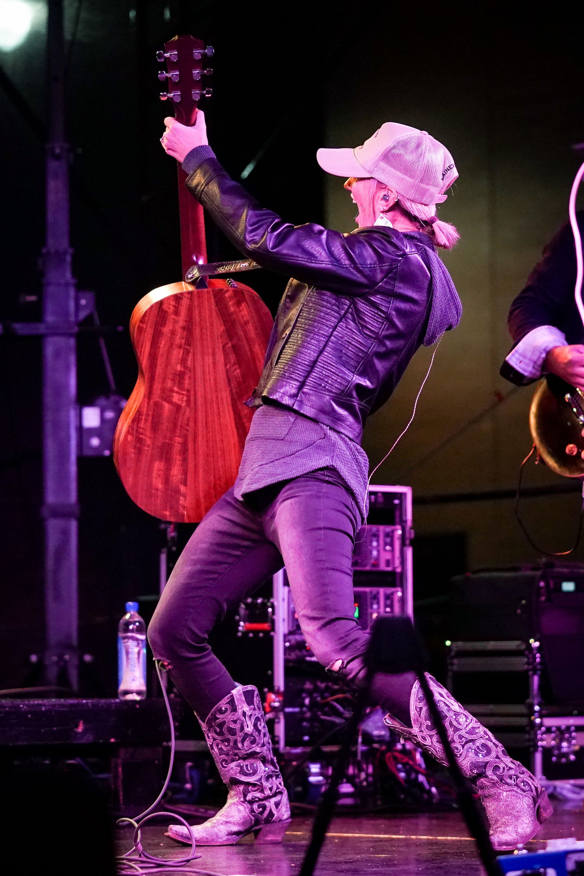 a woman is standing on a stage holding a guitar