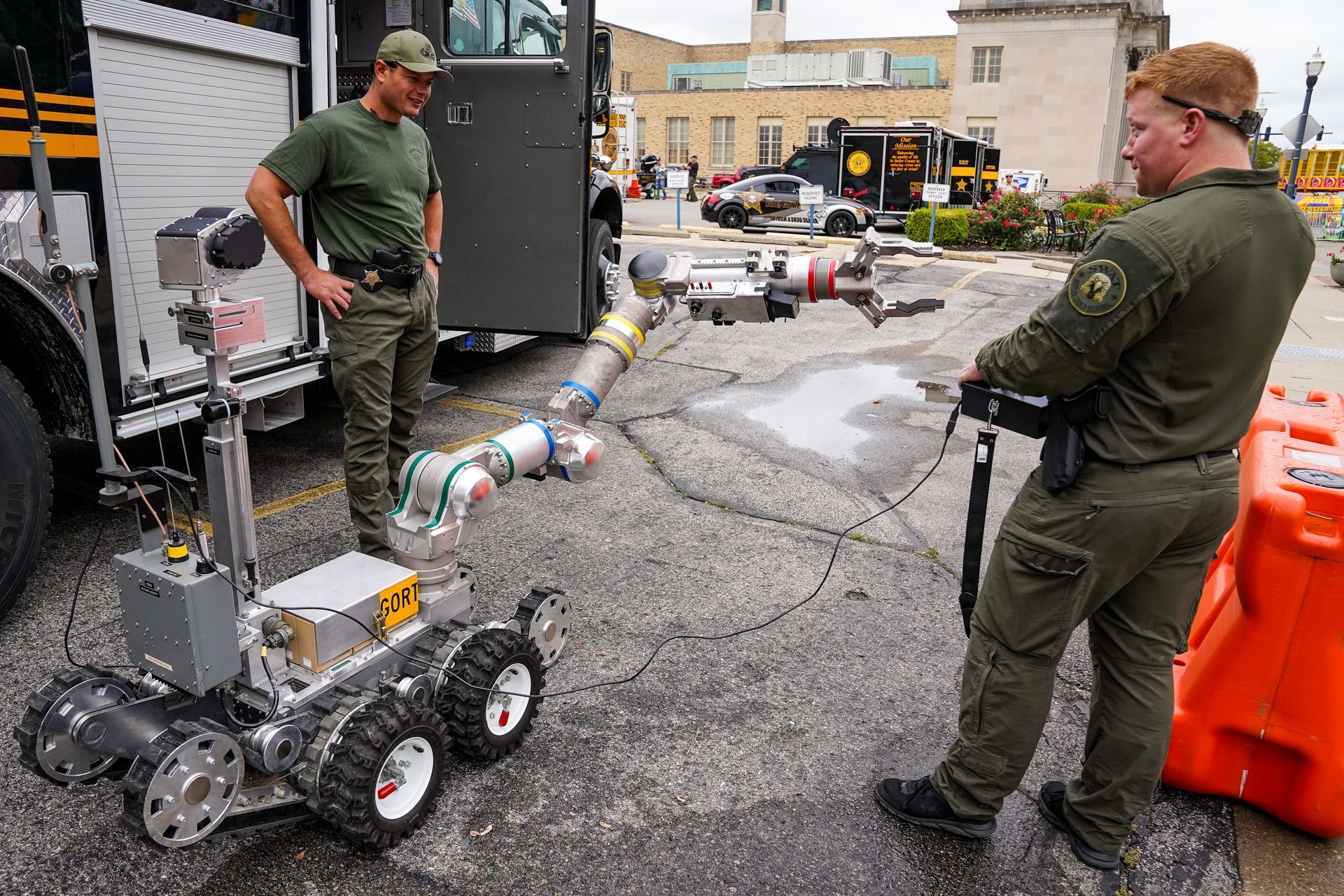 two men are standing next to a robot in front of a fire truck