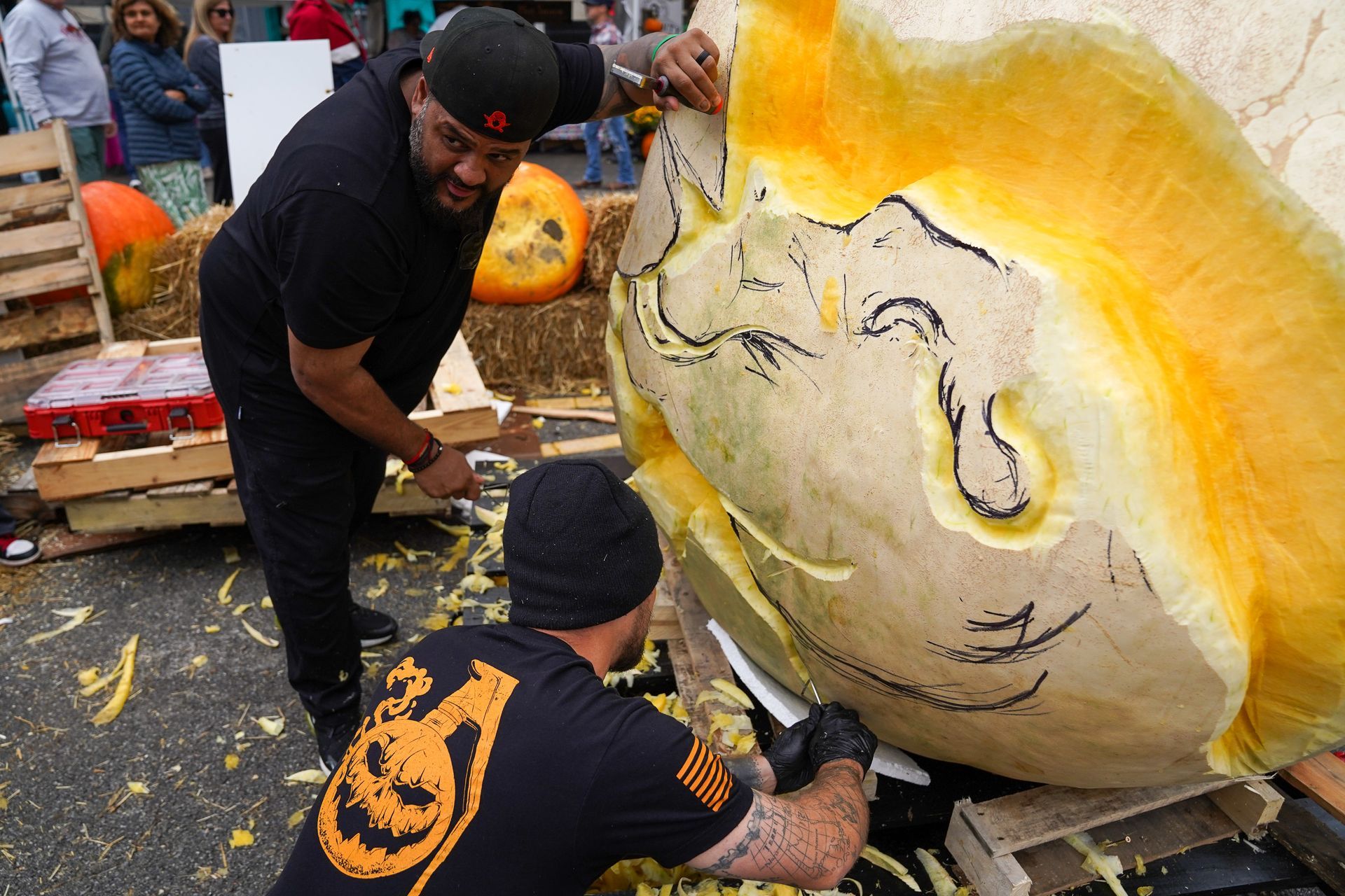 2 man carving a large pumpkin