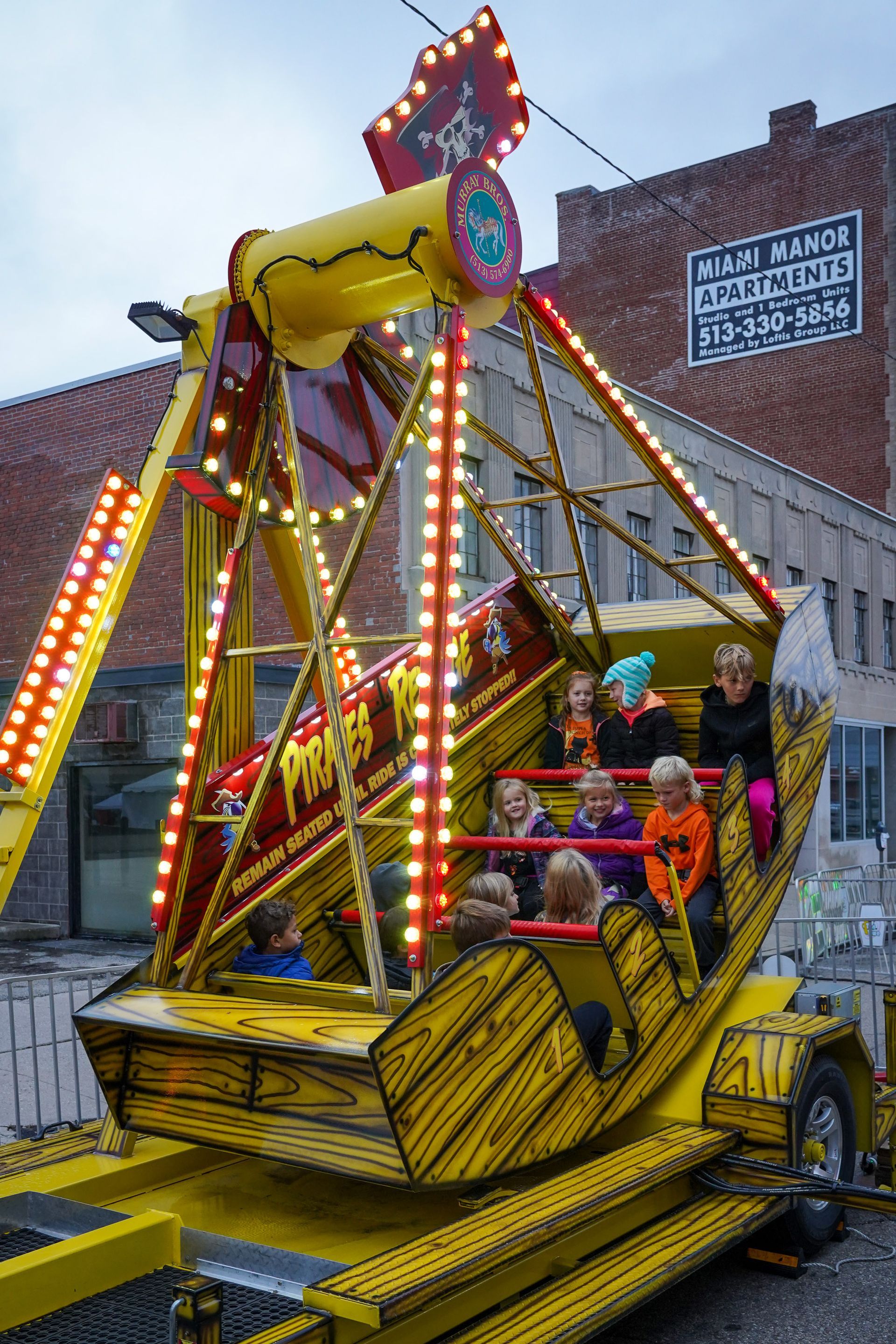 a group of children are riding a carnival ride in front of a building