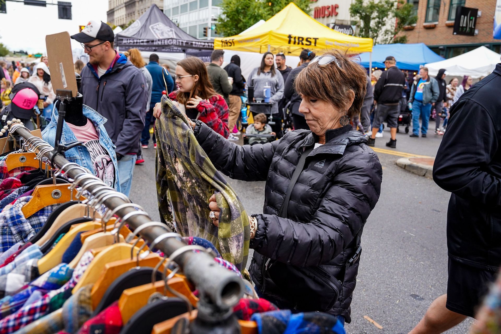 a woman is looking at clothes on a rack at a flea market
