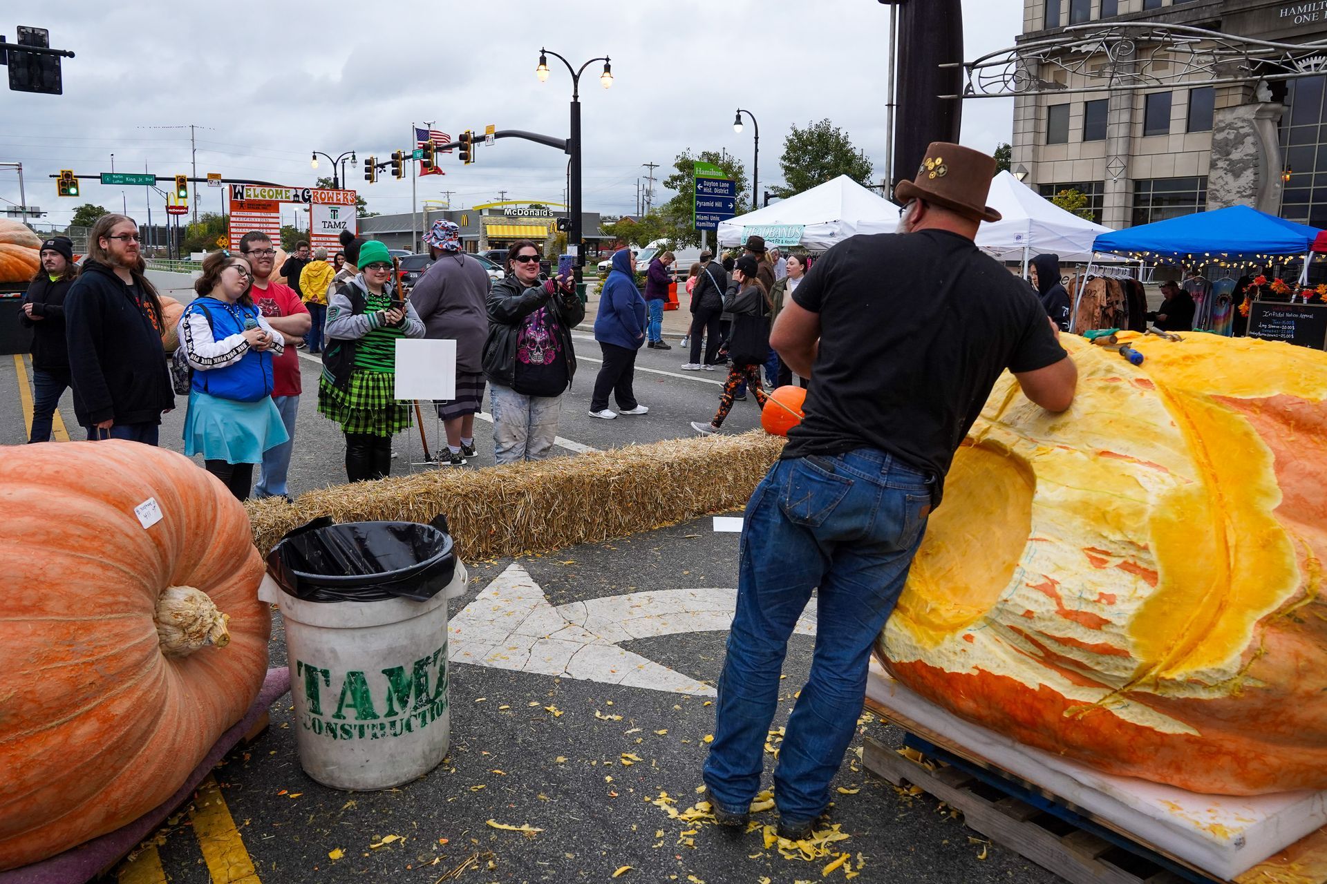 a man in a top hat is standing next to a large pumpkin