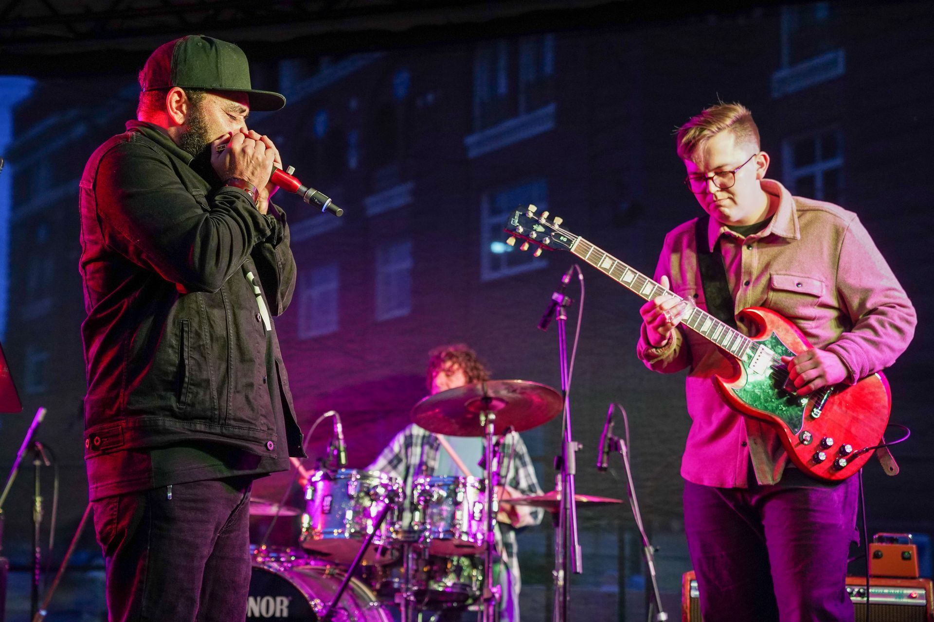 a man is singing into a microphone while another man plays a guitar on stage