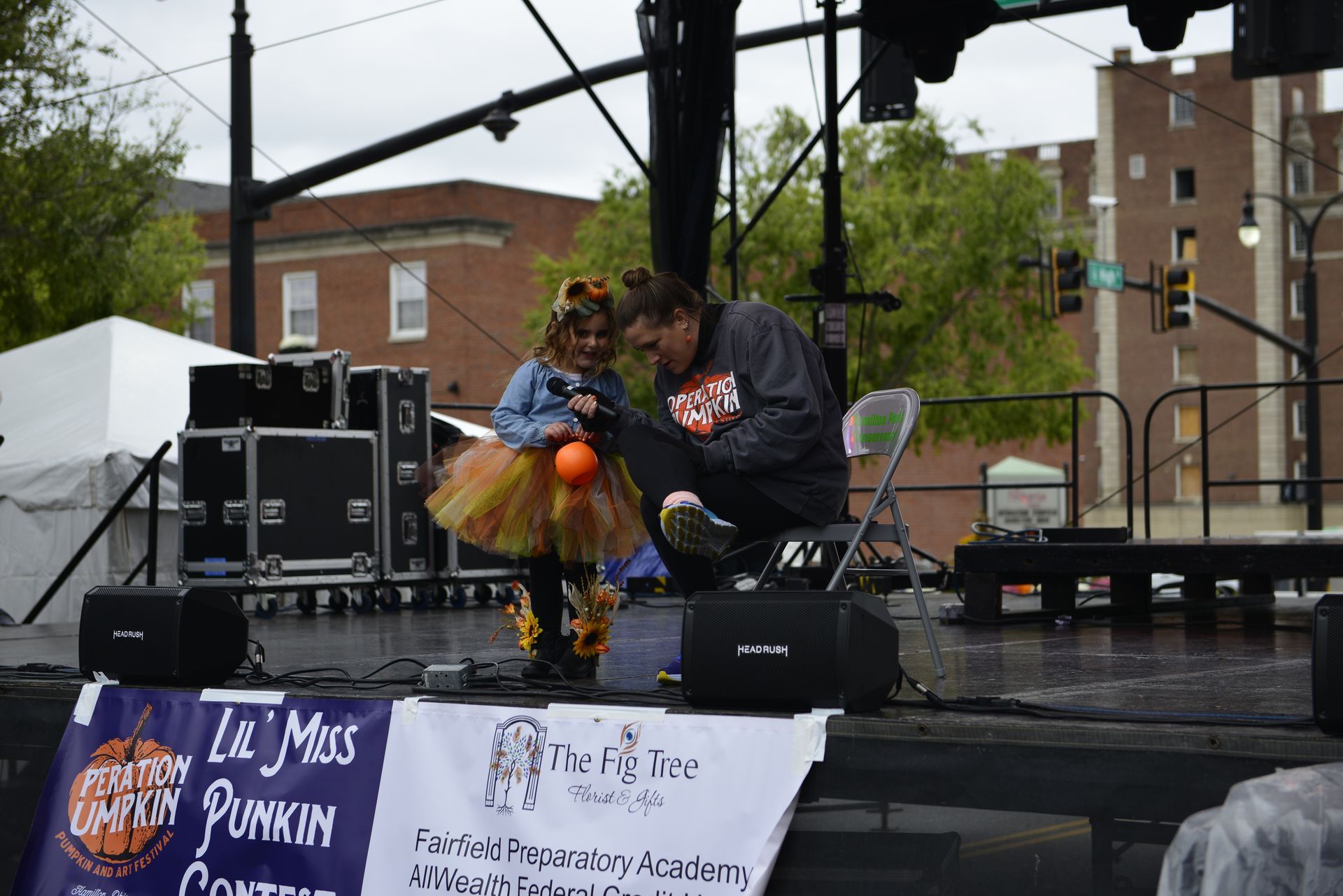 a man and a little girl on a stage with a sign that says le miss pumpkin
