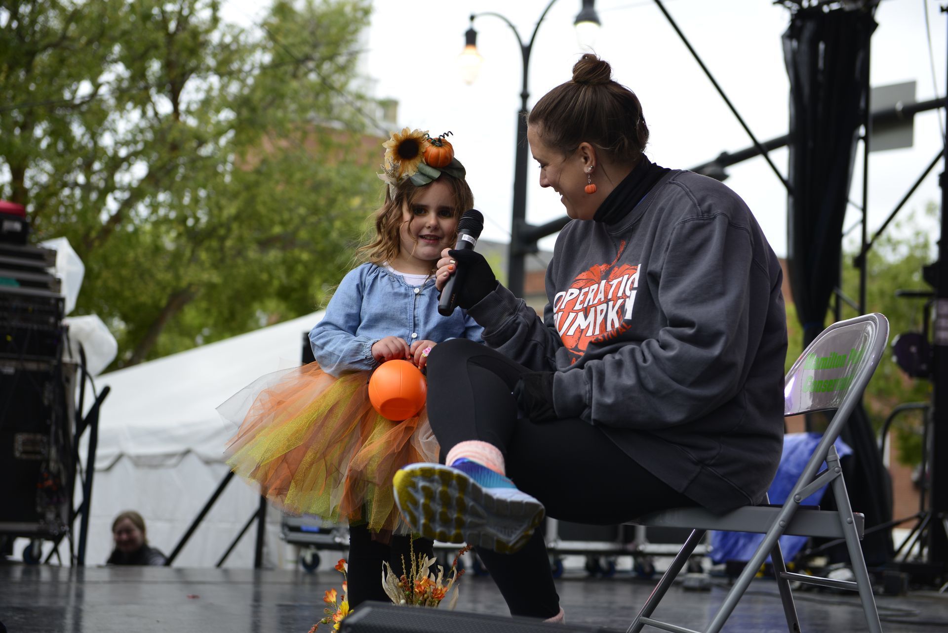 a woman is sitting in a chair next to a little girl on a stage