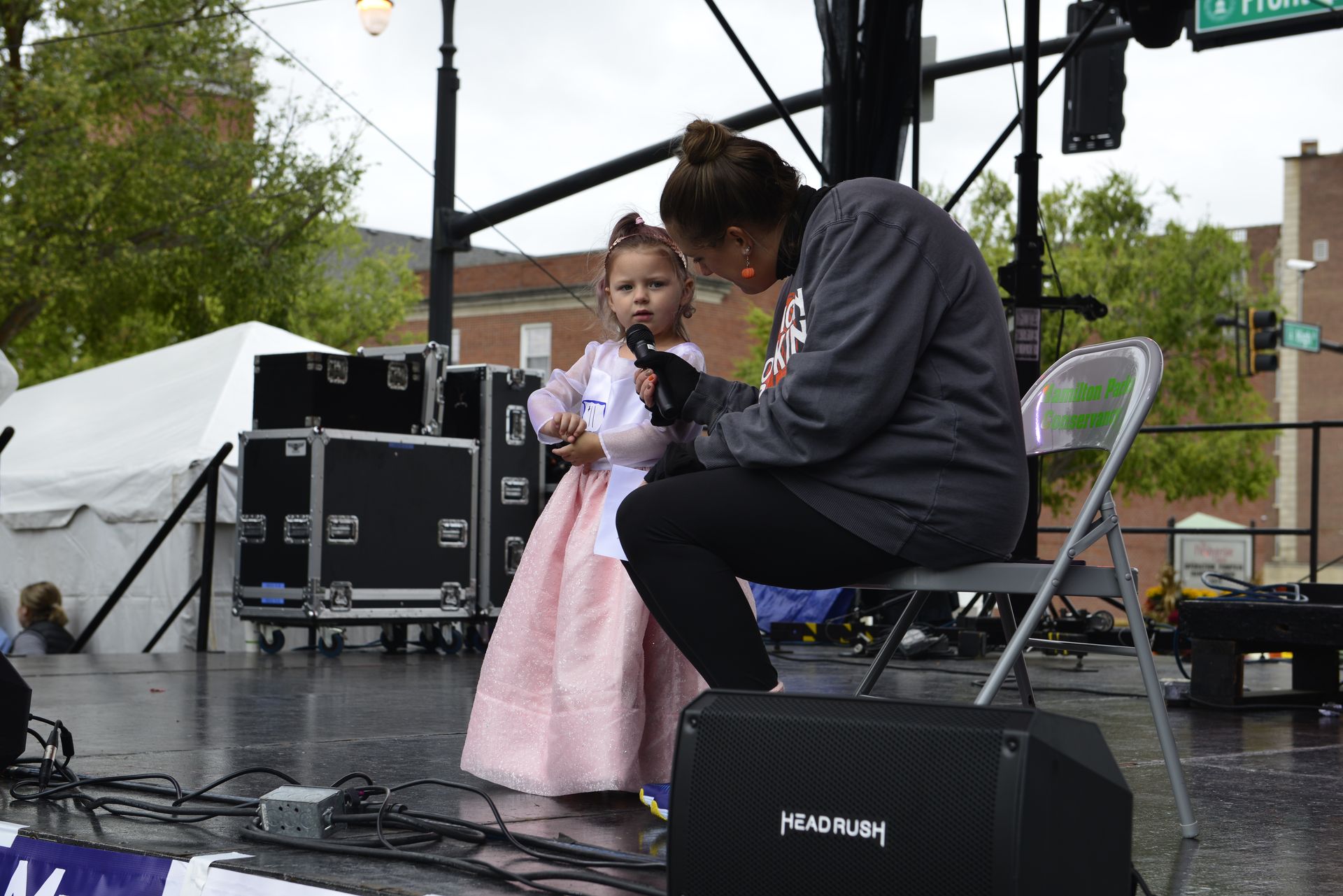 a woman is kneeling down next to a little girl holding a microphone on a stage