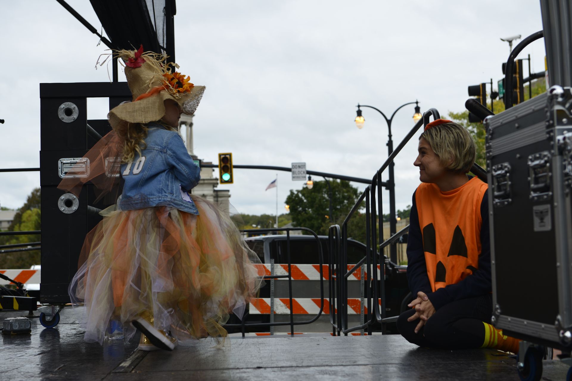 a man is sitting on the ground talking to a little girl in a halloween costume
