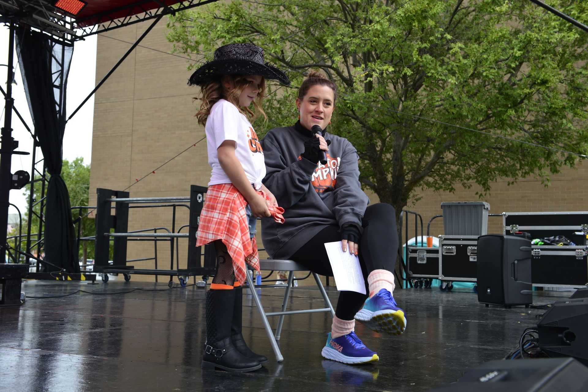 a woman is sitting next to a little girl on a stage holding a microphone