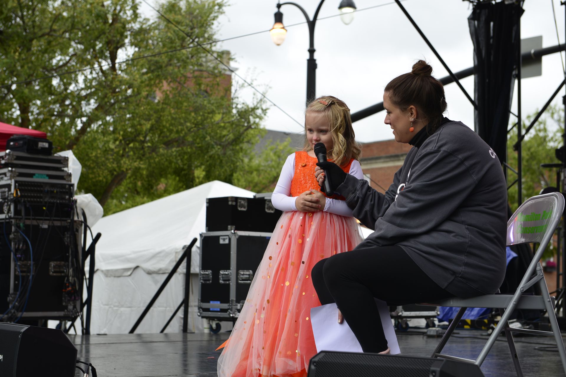 a woman is sitting next to a little girl on a stage holding a microphone