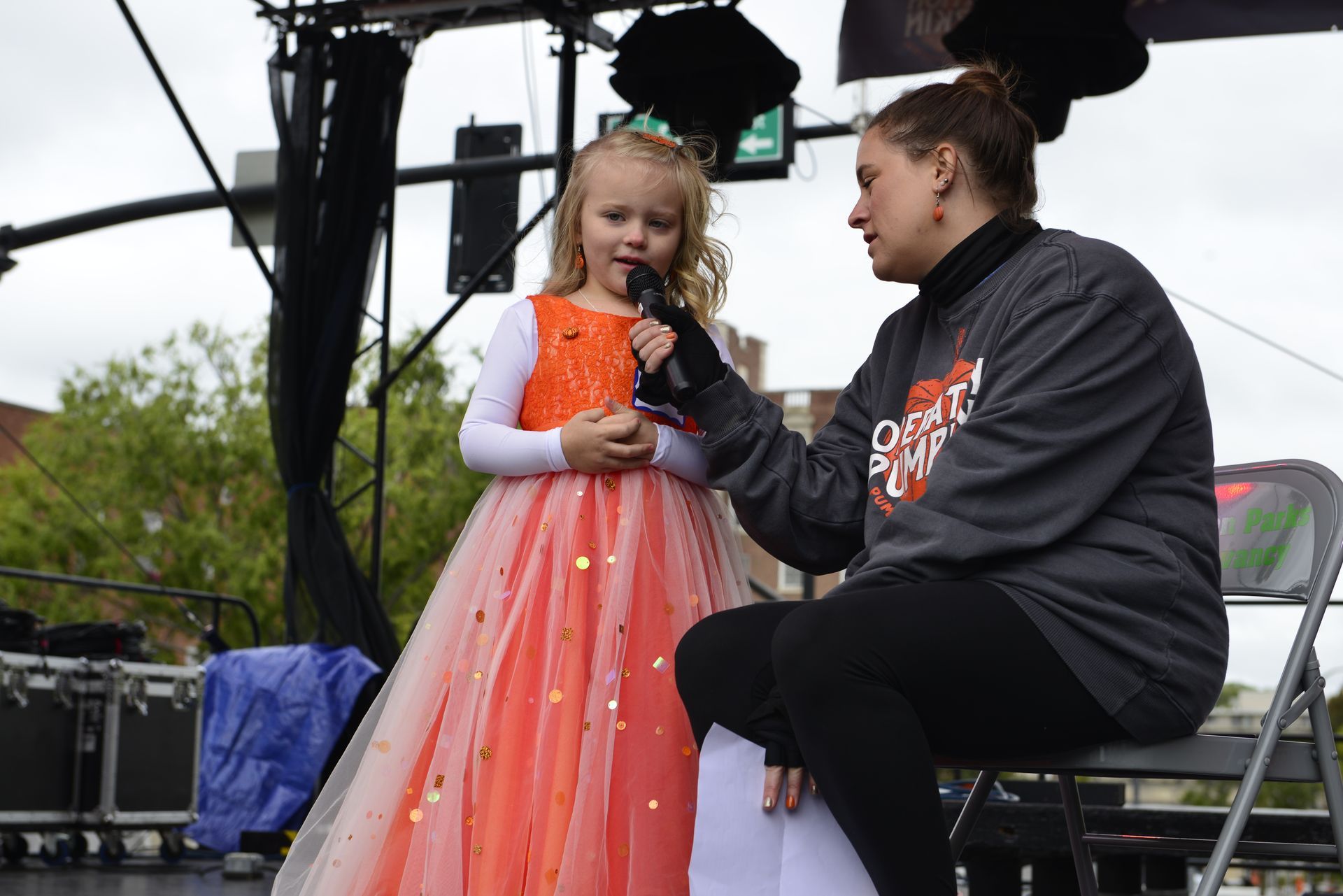 a woman is sitting next to a little girl holding a microphone