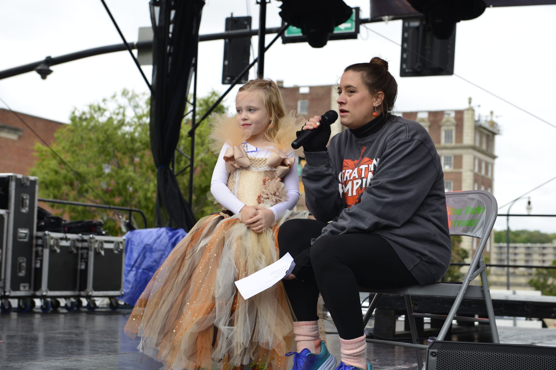 a woman is sitting next to a little girl holding a microphone