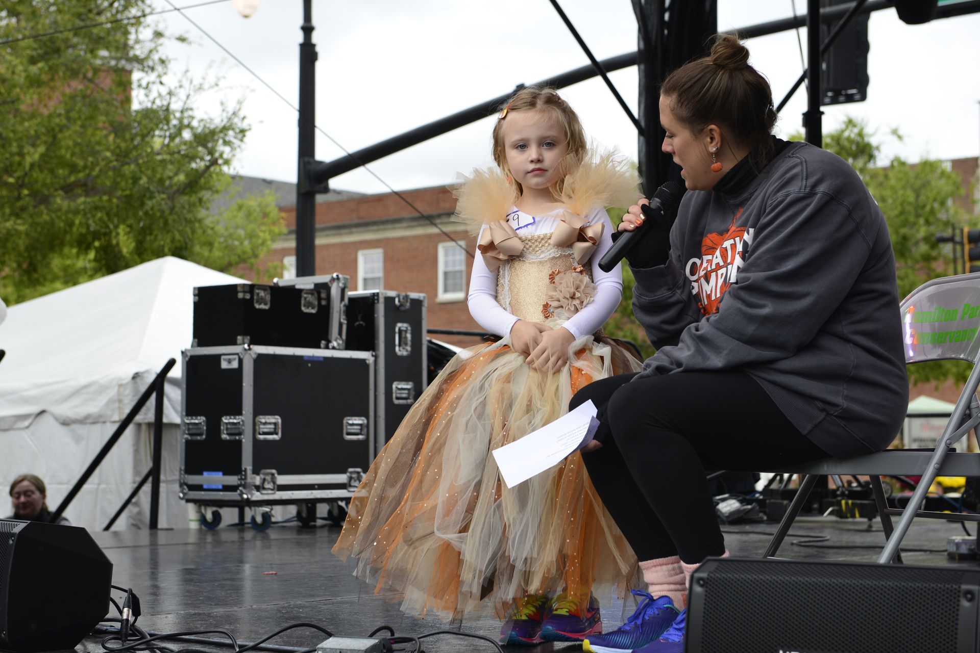 a woman is sitting next to a little girl on a stage holding a microphone