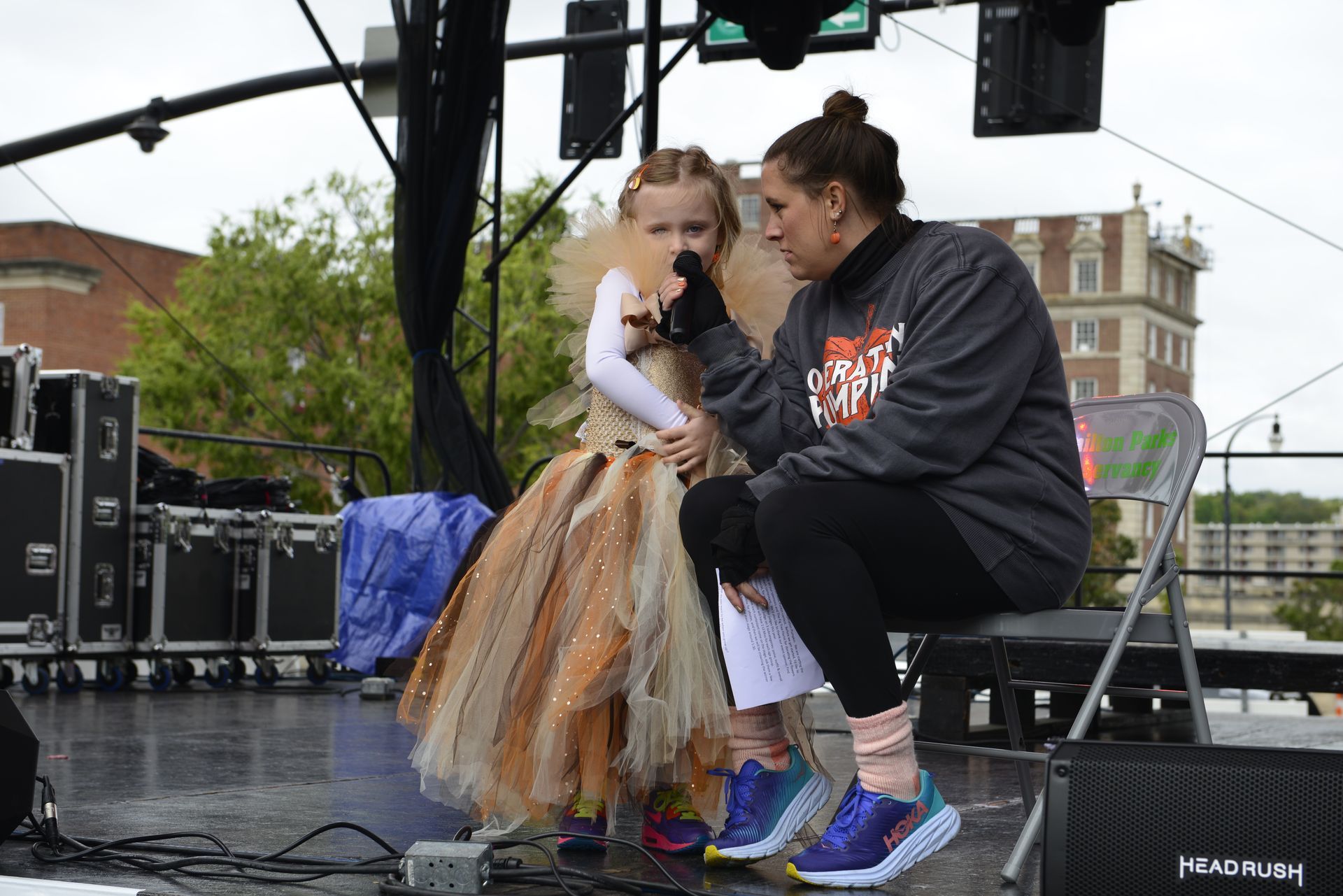 a woman is sitting next to a little girl on a stage holding a microphone
