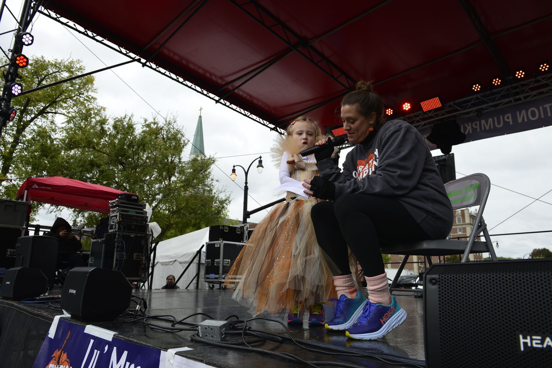 a woman is sitting next to a little girl on a stage holding a microphone