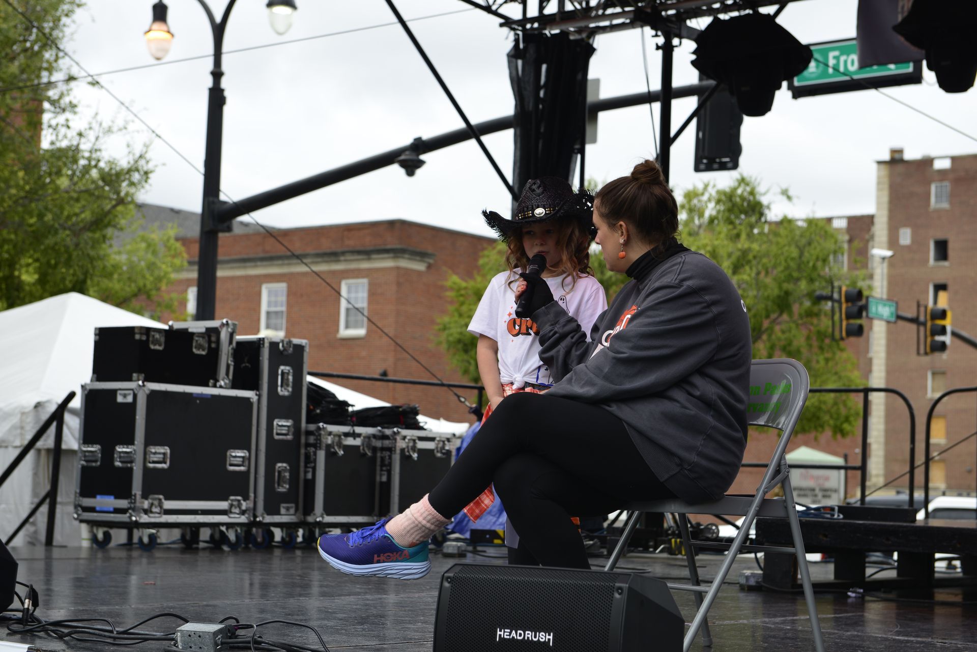 a woman in a cowboy hat is sitting on a stage talking into a microphone