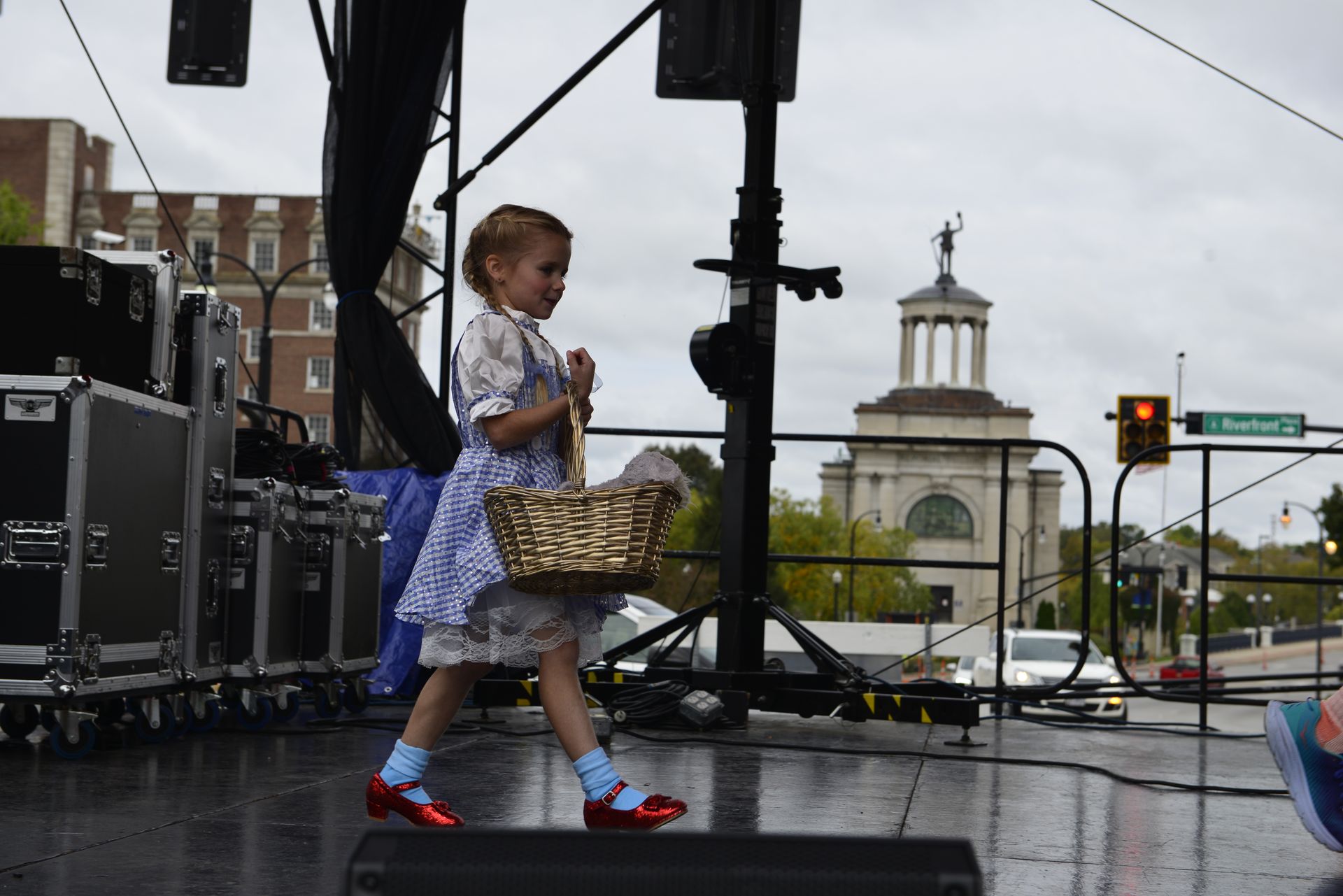 a little girl in a wizard of oz costume is walking on a stage