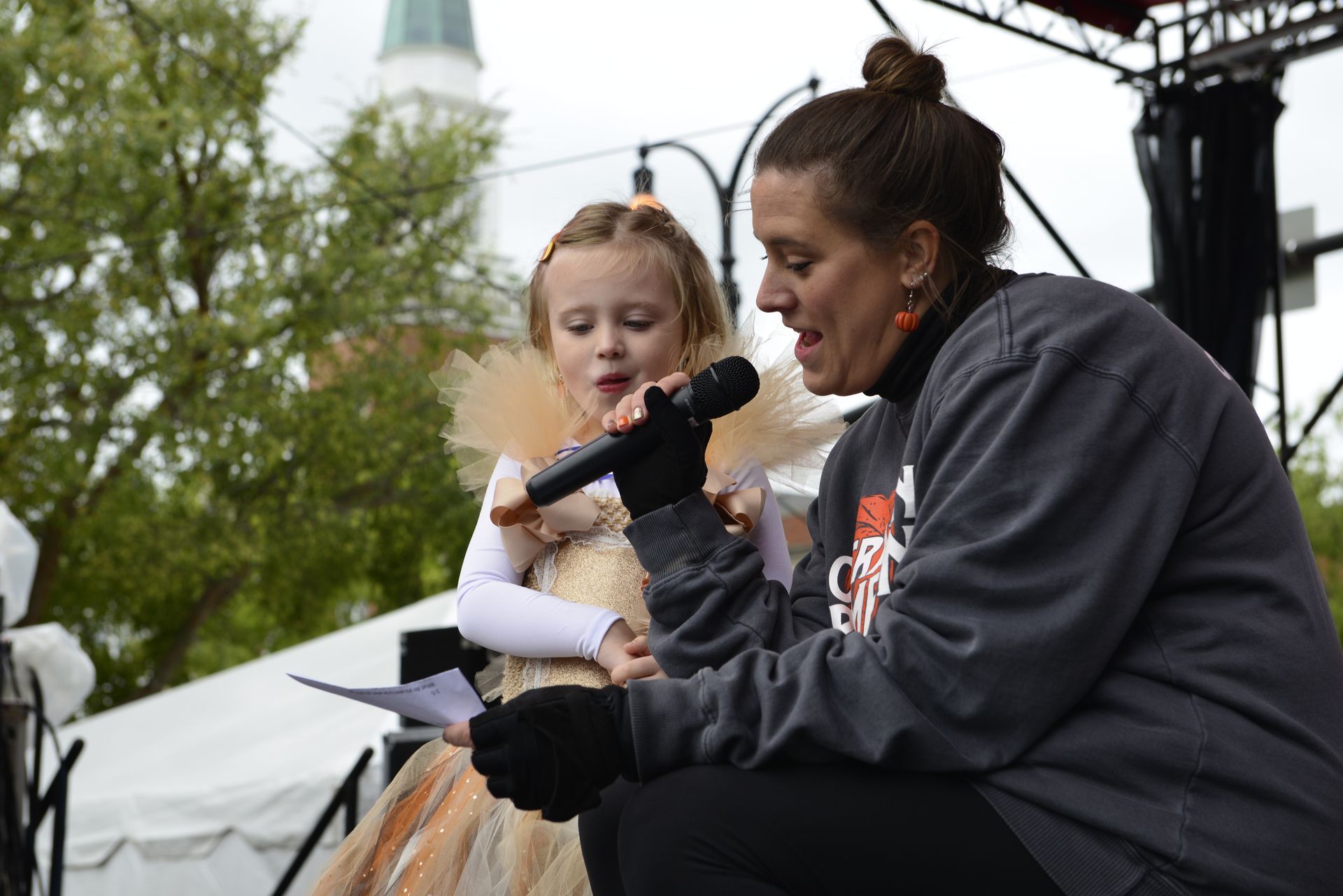 a woman is kneeling down next to a little girl holding a microphone