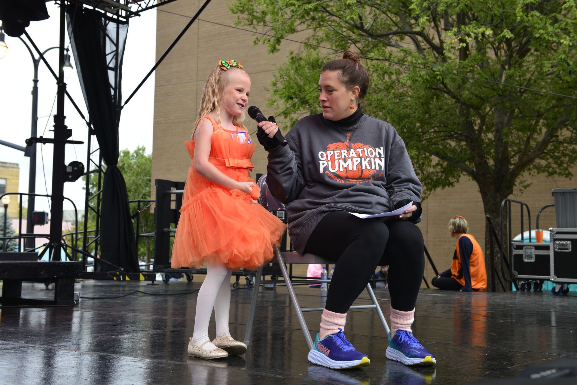 a little girl is standing next to a woman holding a microphone