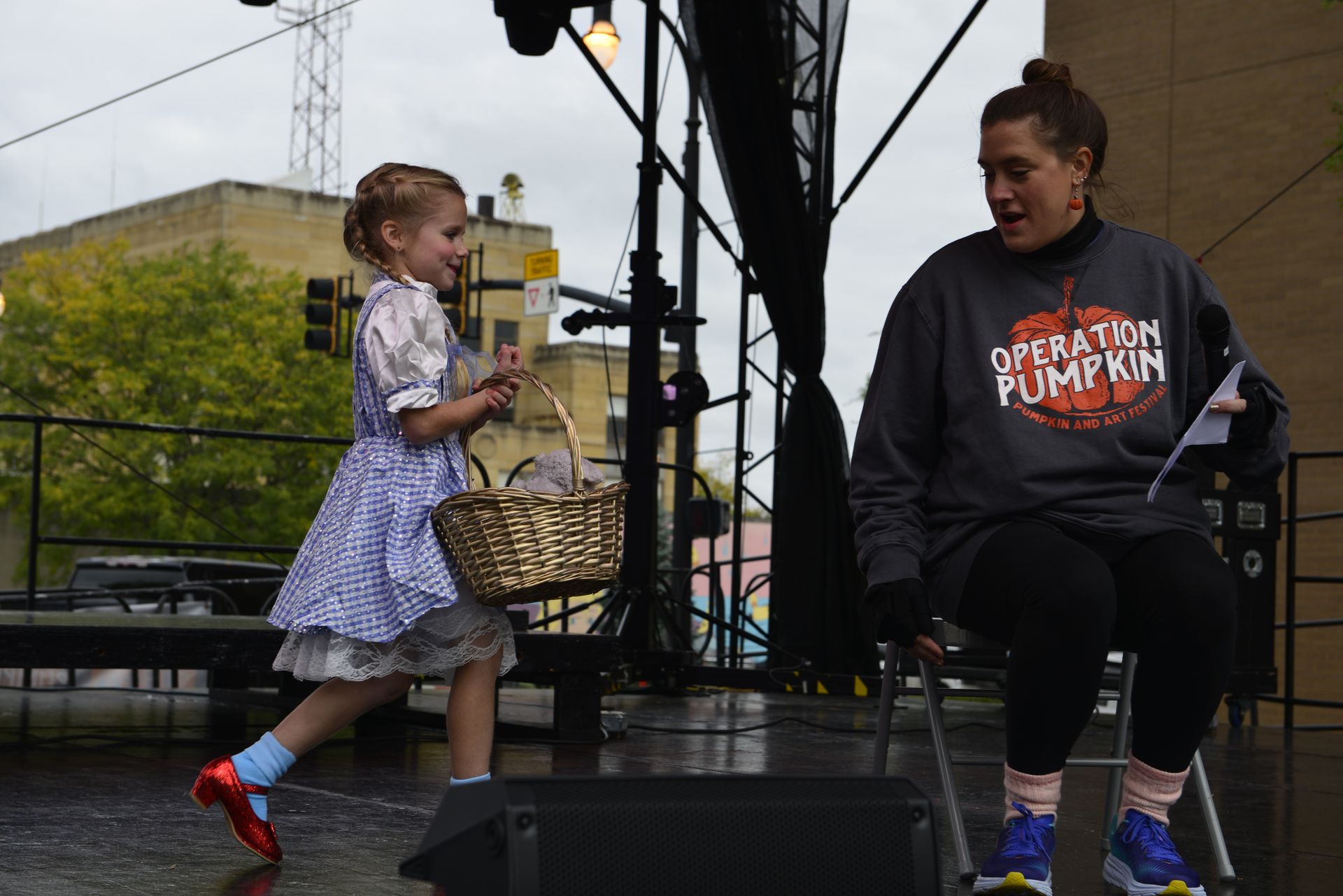 a little girl in a wizard of oz costume is standing next to a woman in an operation pumpkin sweatshirt