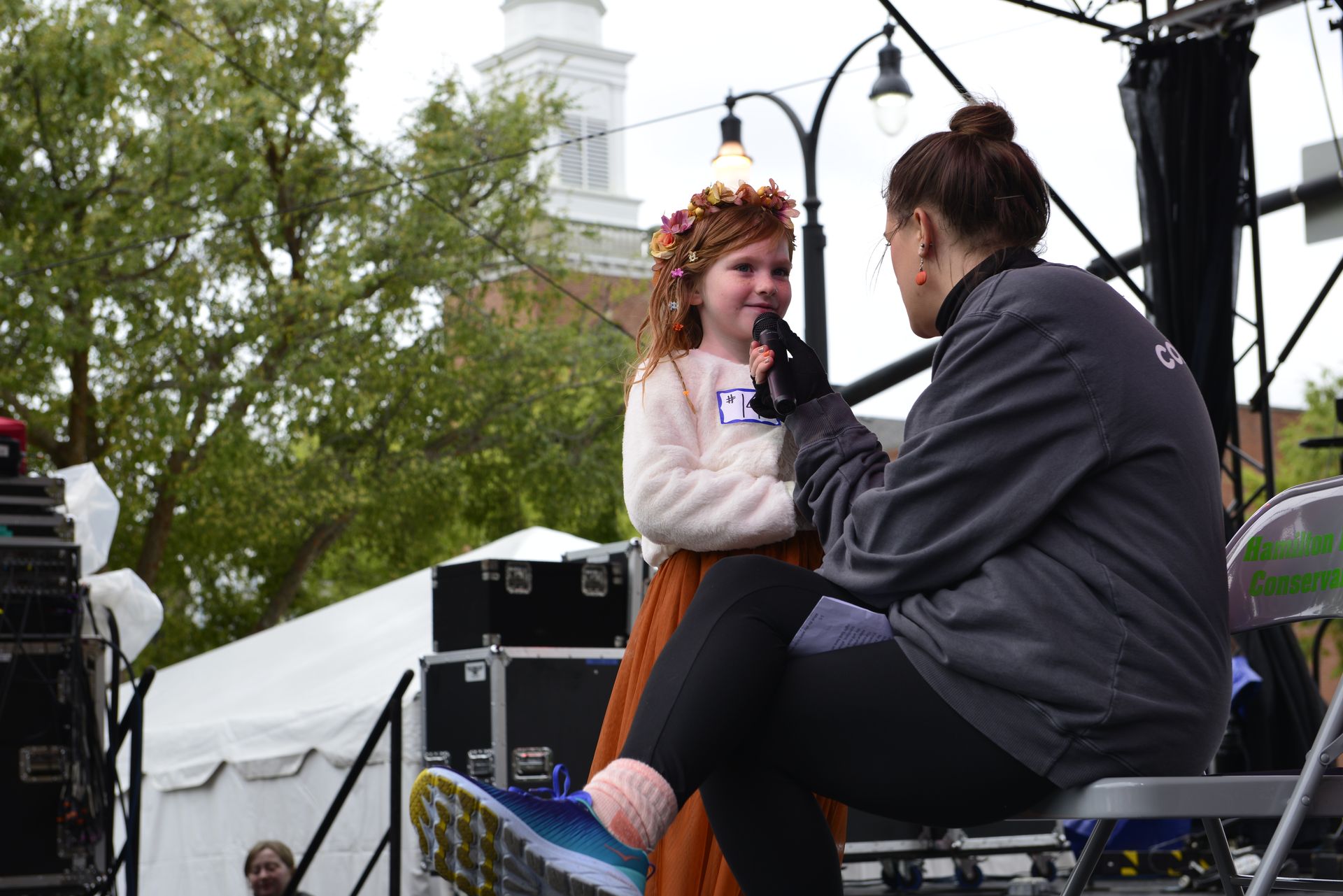 a woman is talking to a little girl who is wearing a flower crown