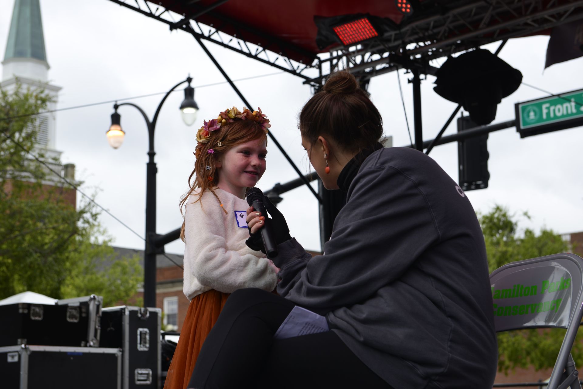 a woman is interviewing a little girl who is wearing a flower crown