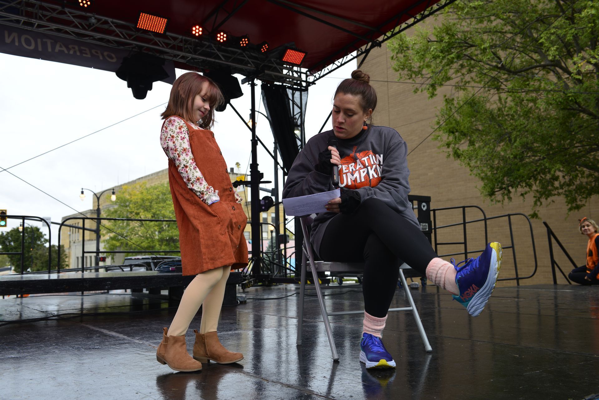 a woman is sitting on a chair next to a little girl on a stage