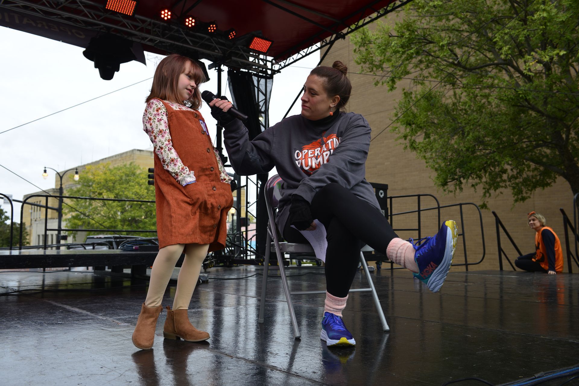 a woman is holding a microphone next to a little girl on a stage