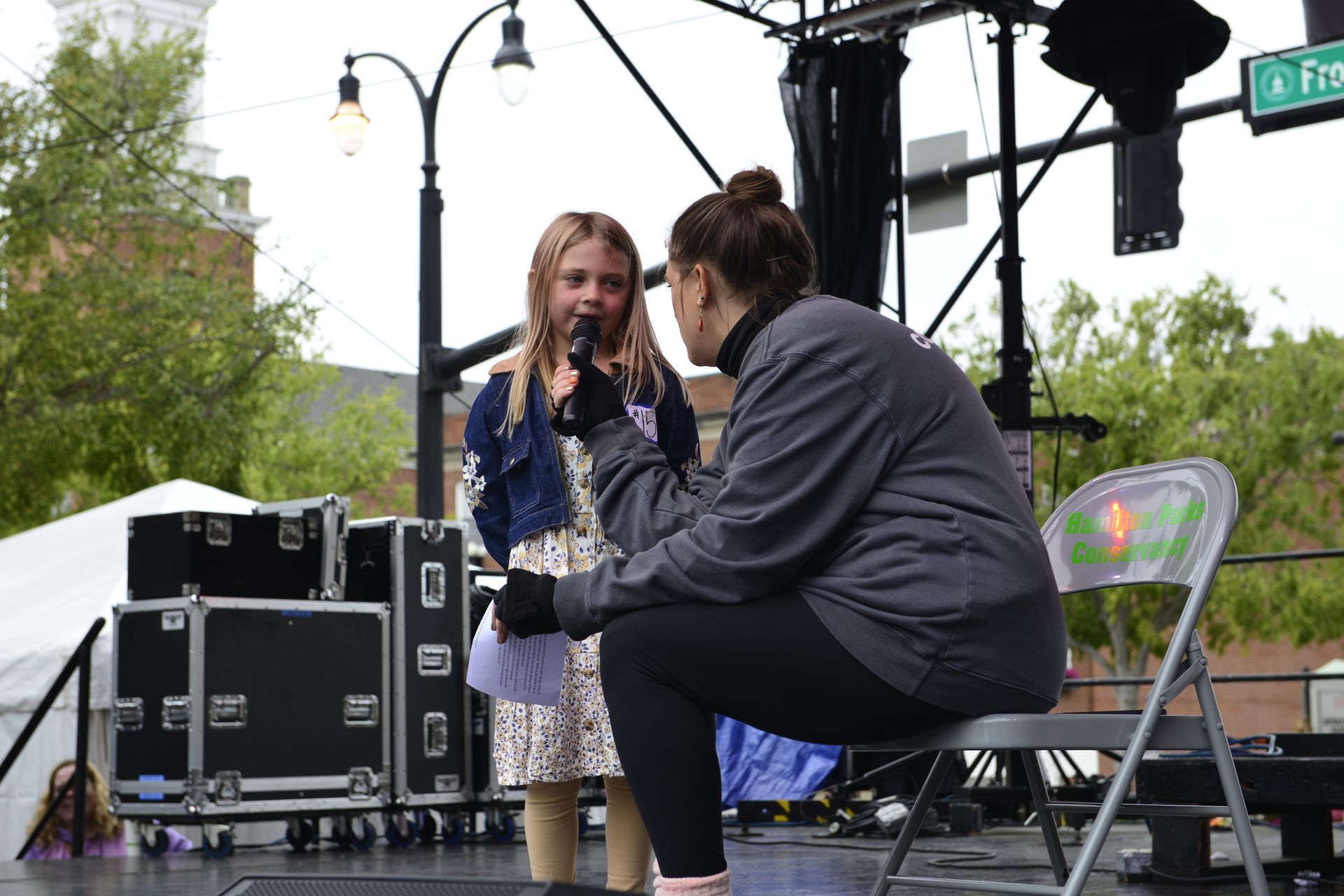 a woman is kneeling down next to a little girl holding a microphone