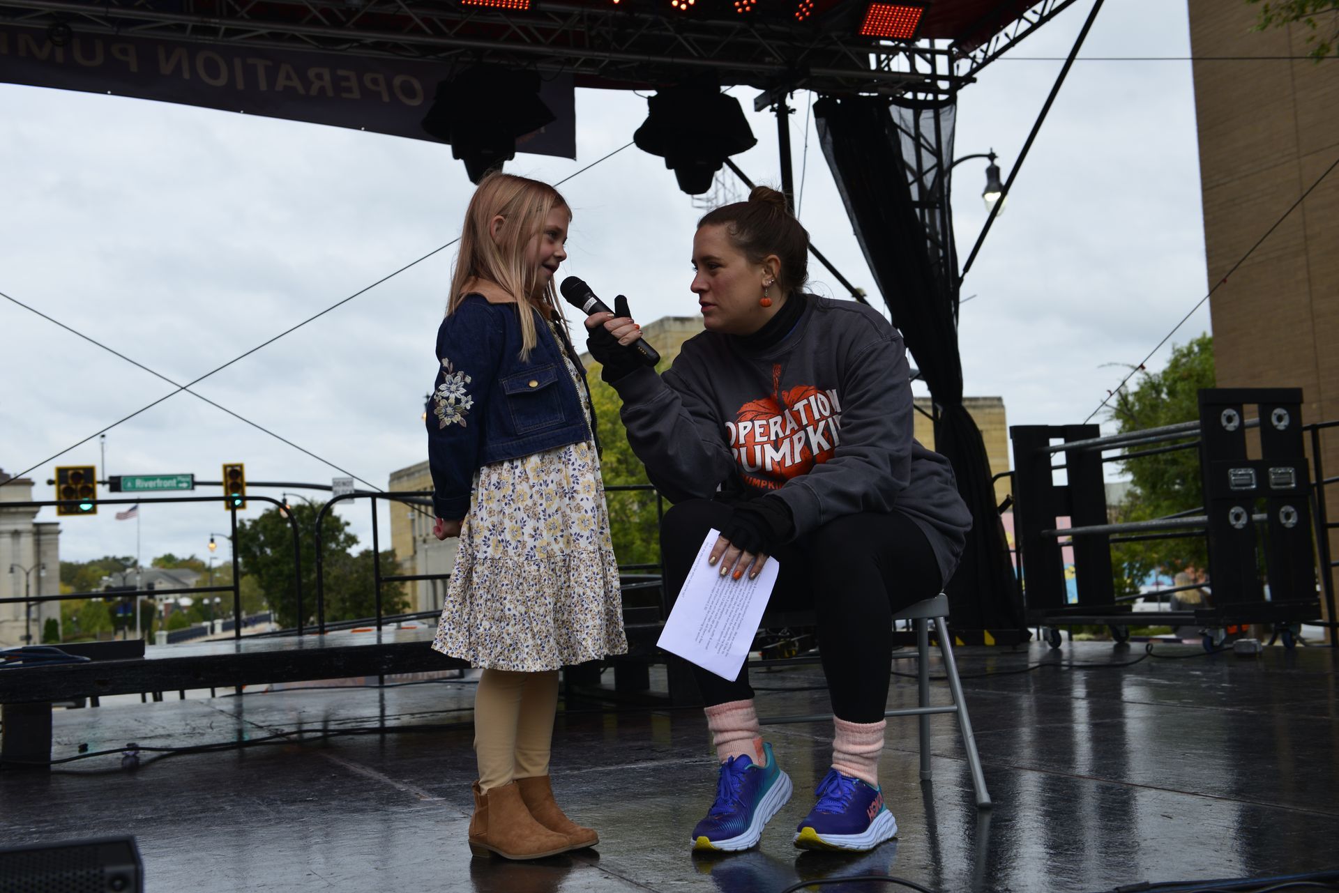 a woman is talking to a little girl on a stage with a microphone