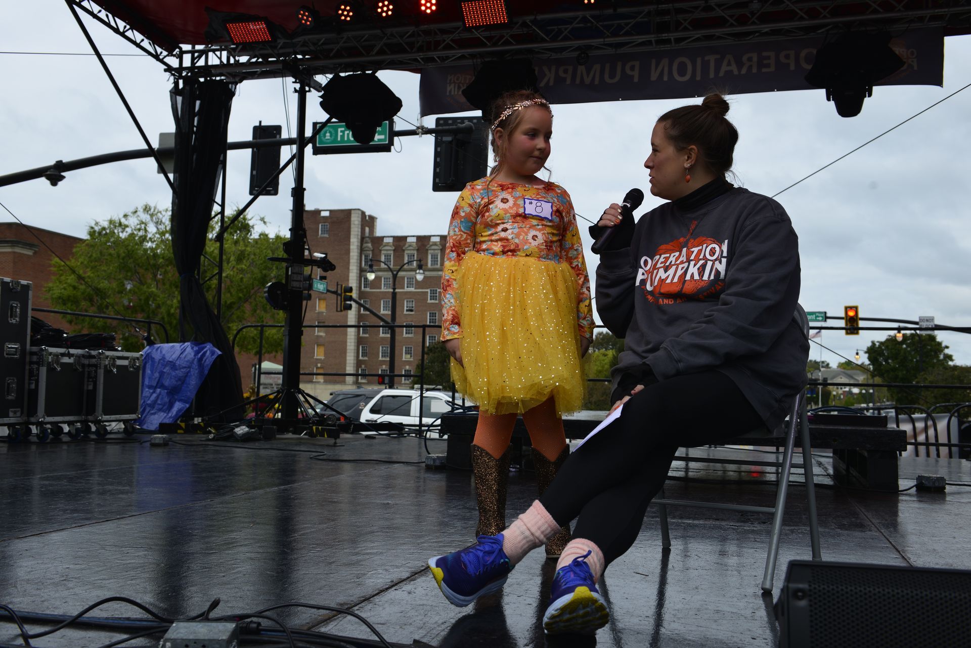 a woman is sitting next to a little girl on a stage talking into a microphone