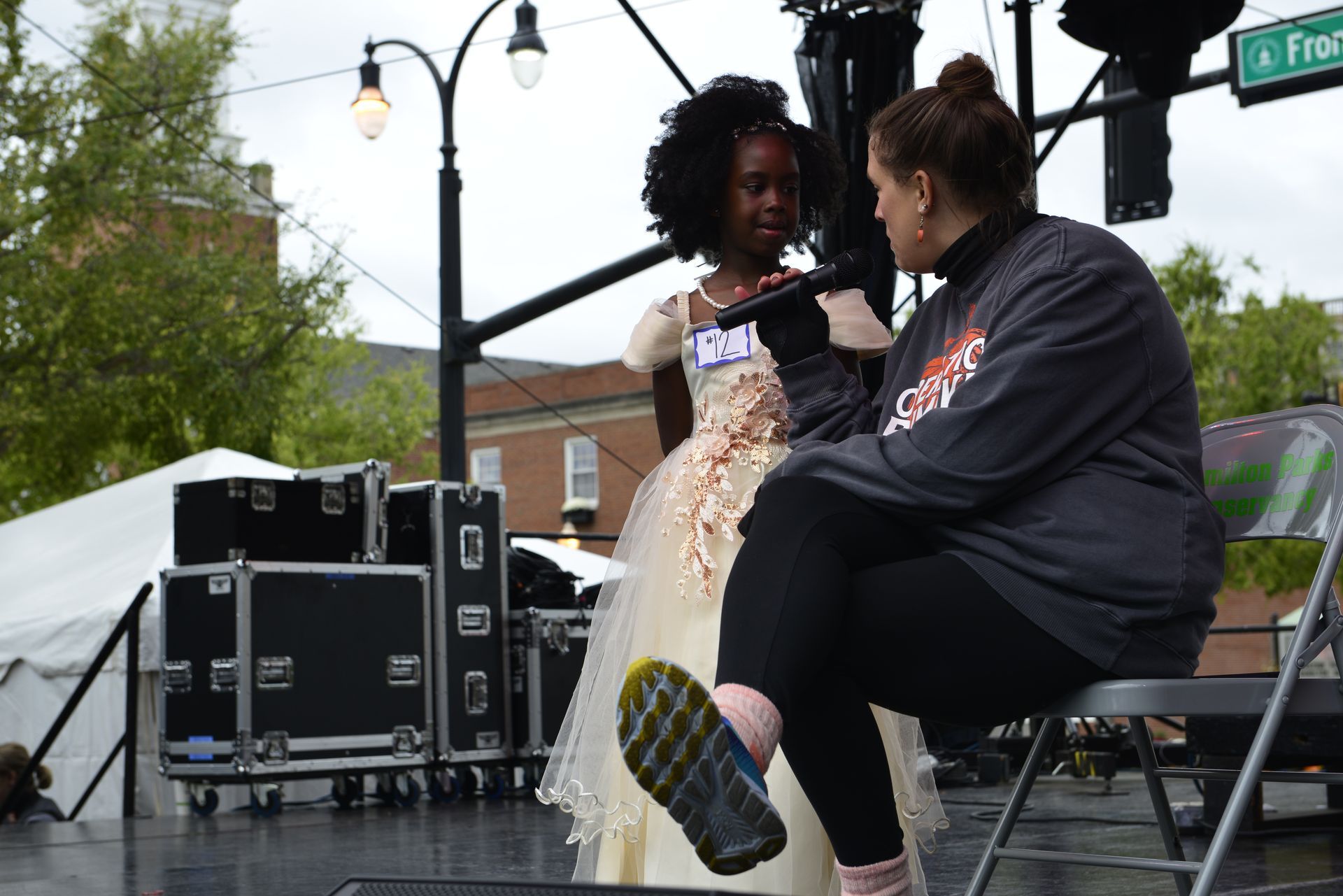 a woman is sitting in a chair talking to a little girl in a dress