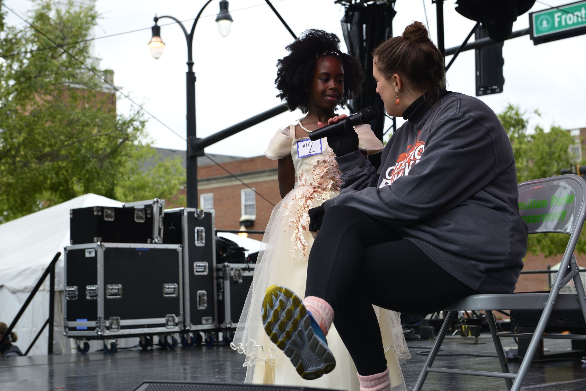 a woman is sitting next to a little girl in a dress on a stage