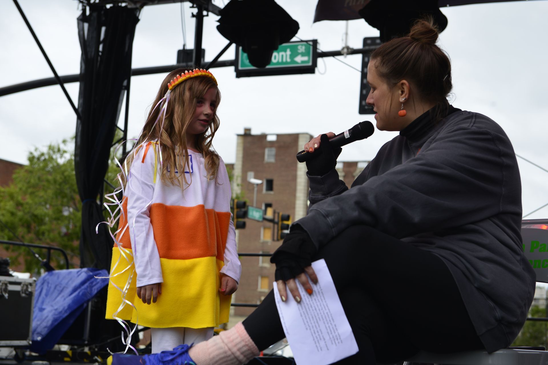 a woman is sitting next to a little girl in a candy corn costume