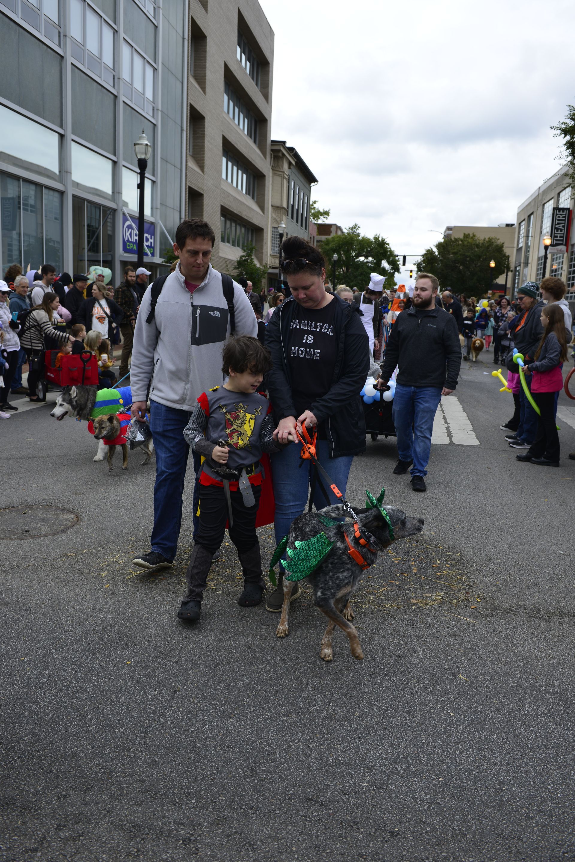 a man and a boy are walking a dog down a street