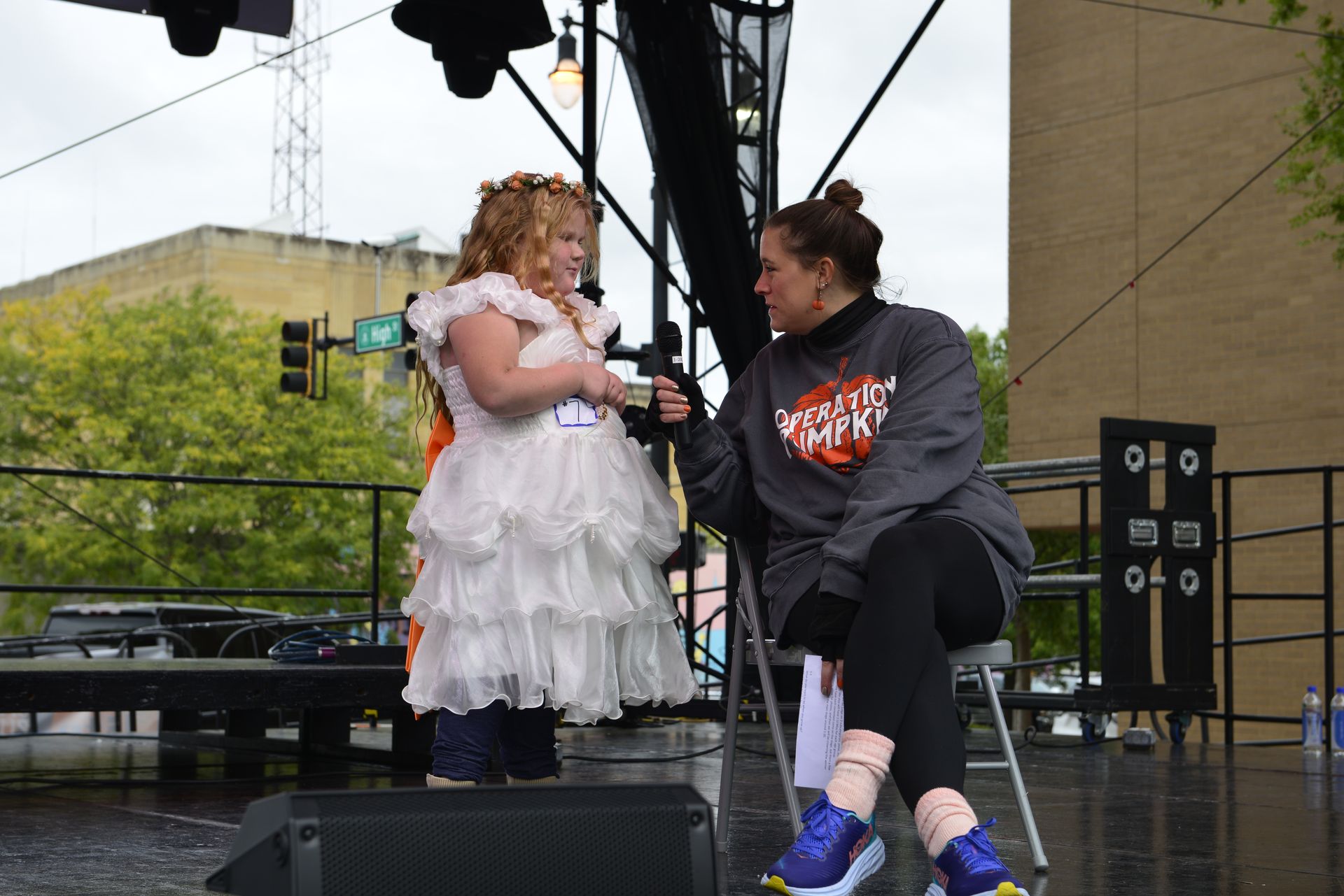 a woman is sitting on a chair talking to a little girl in a white dress