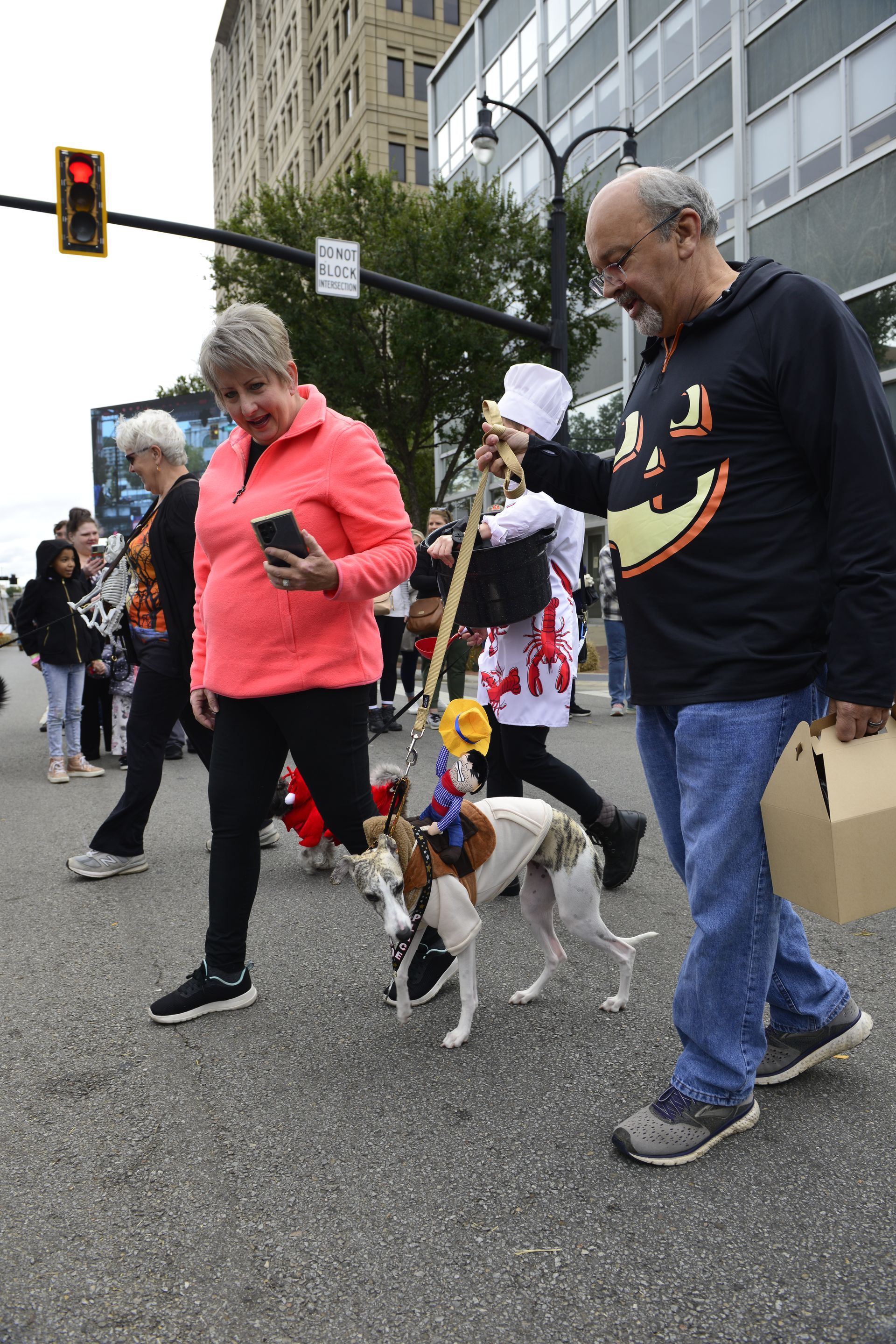 a man and a woman are walking their dogs down the street