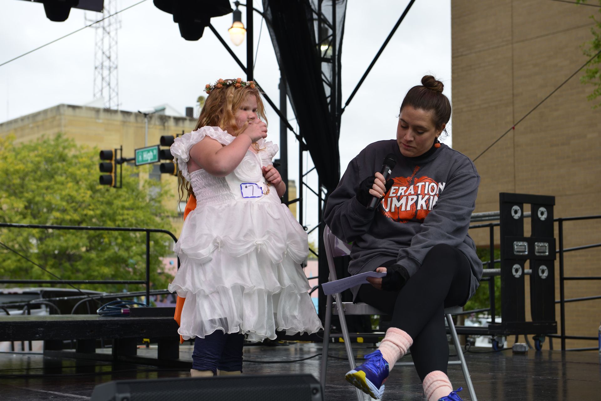 a woman is sitting next to a little girl in a white dress on a stage