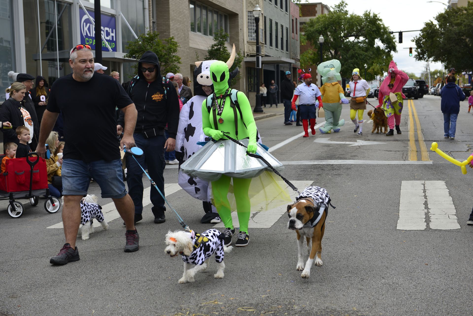 a group of people dressed in costumes are walking their dogs down a street