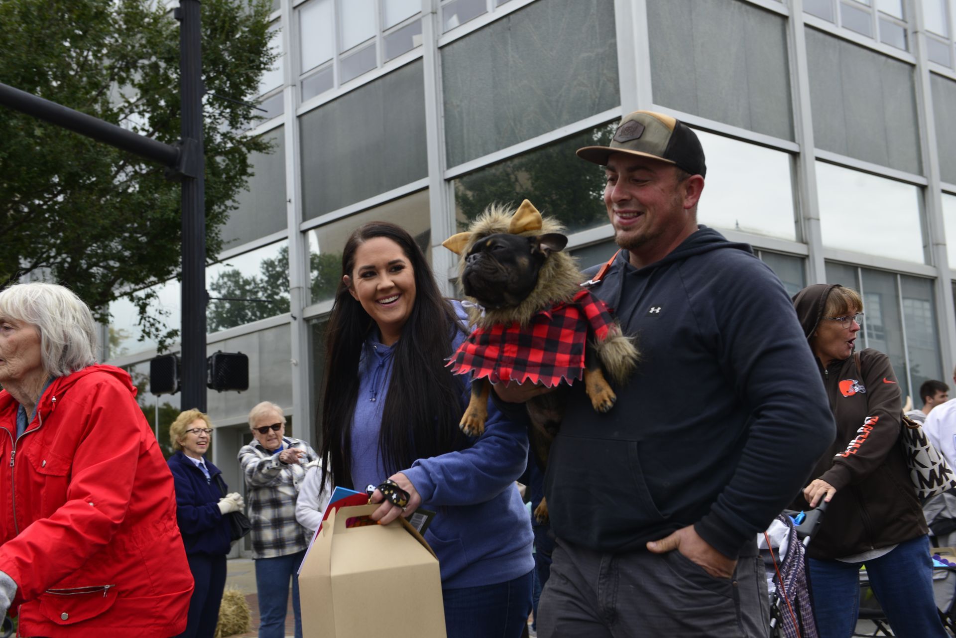 a man and a woman are walking a dog in a plaid shirt