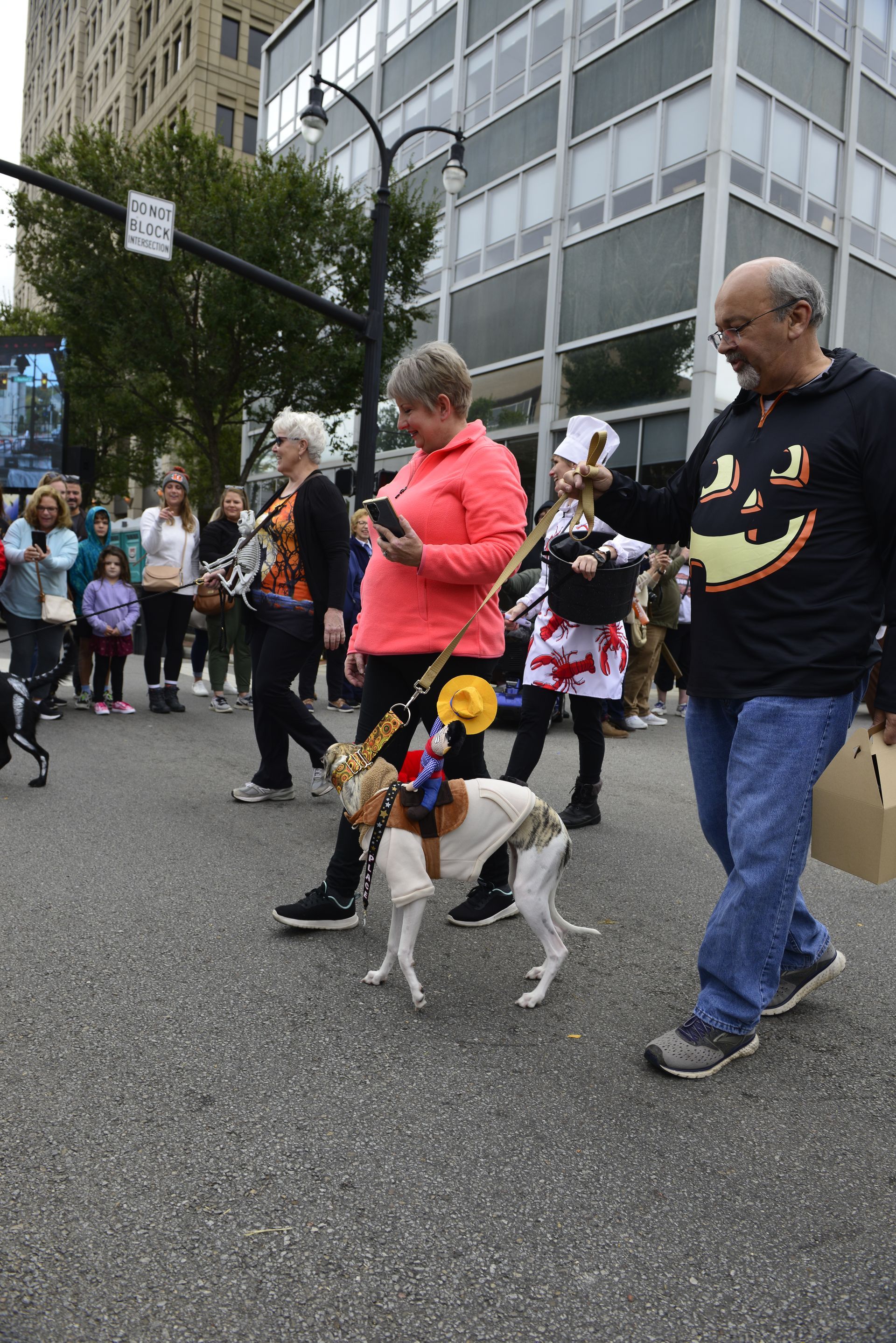 a group of people are walking a dog down a street