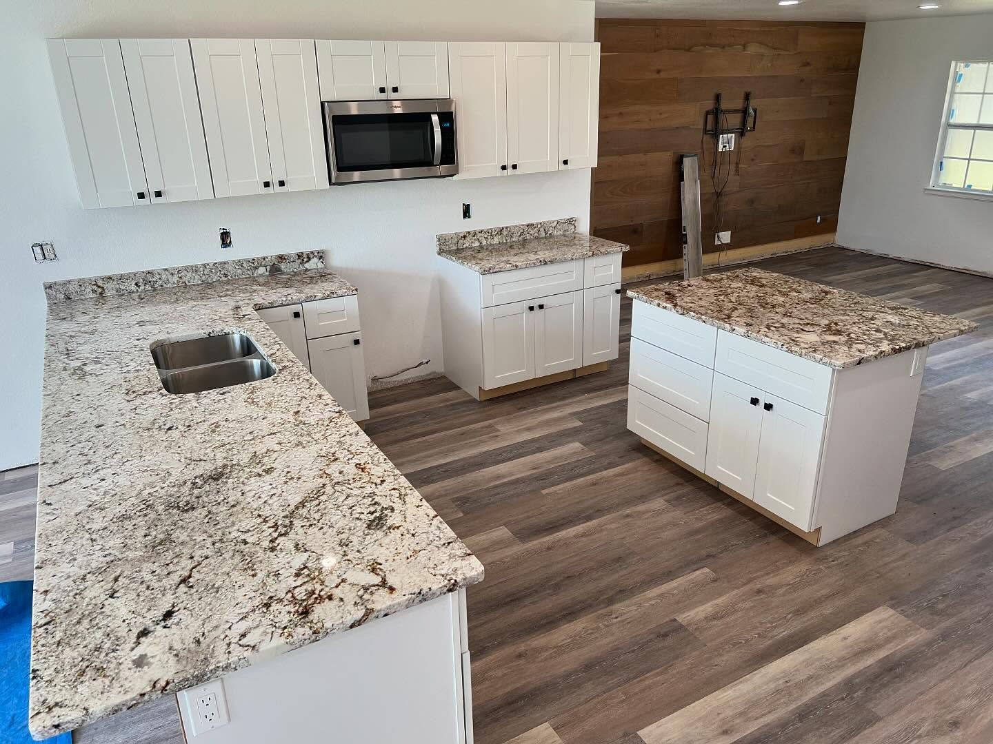 A kitchen with granite counter tops and white cabinets.