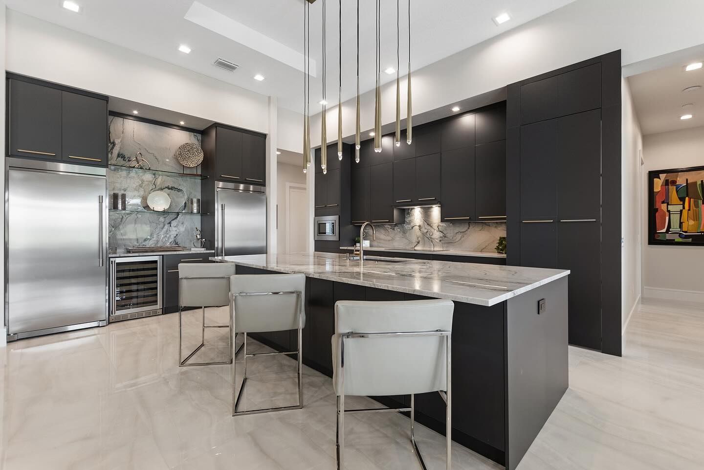 A kitchen with black cabinets and stainless steel appliances and a large island.