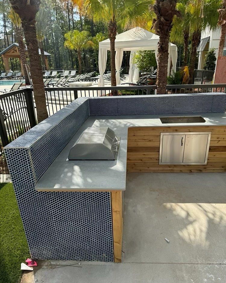 A large outdoor kitchen with a grill and a sink.