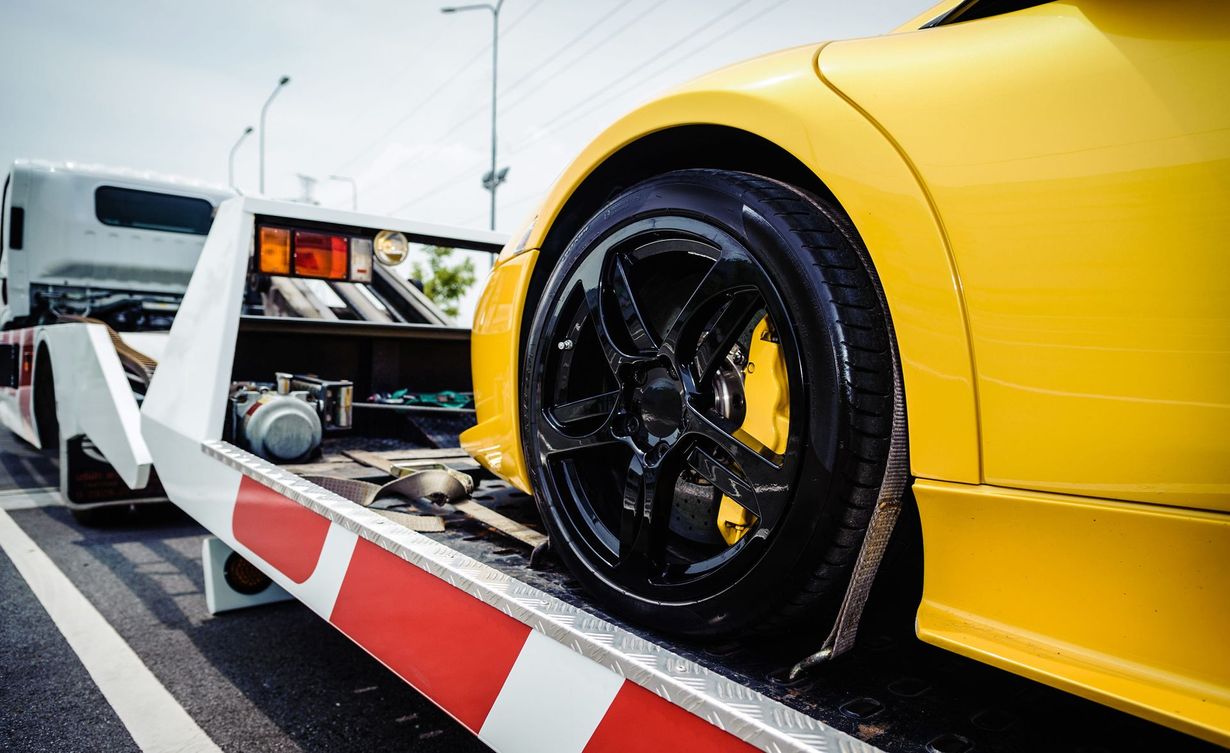 Yellow sports car being towed by a tow truck.