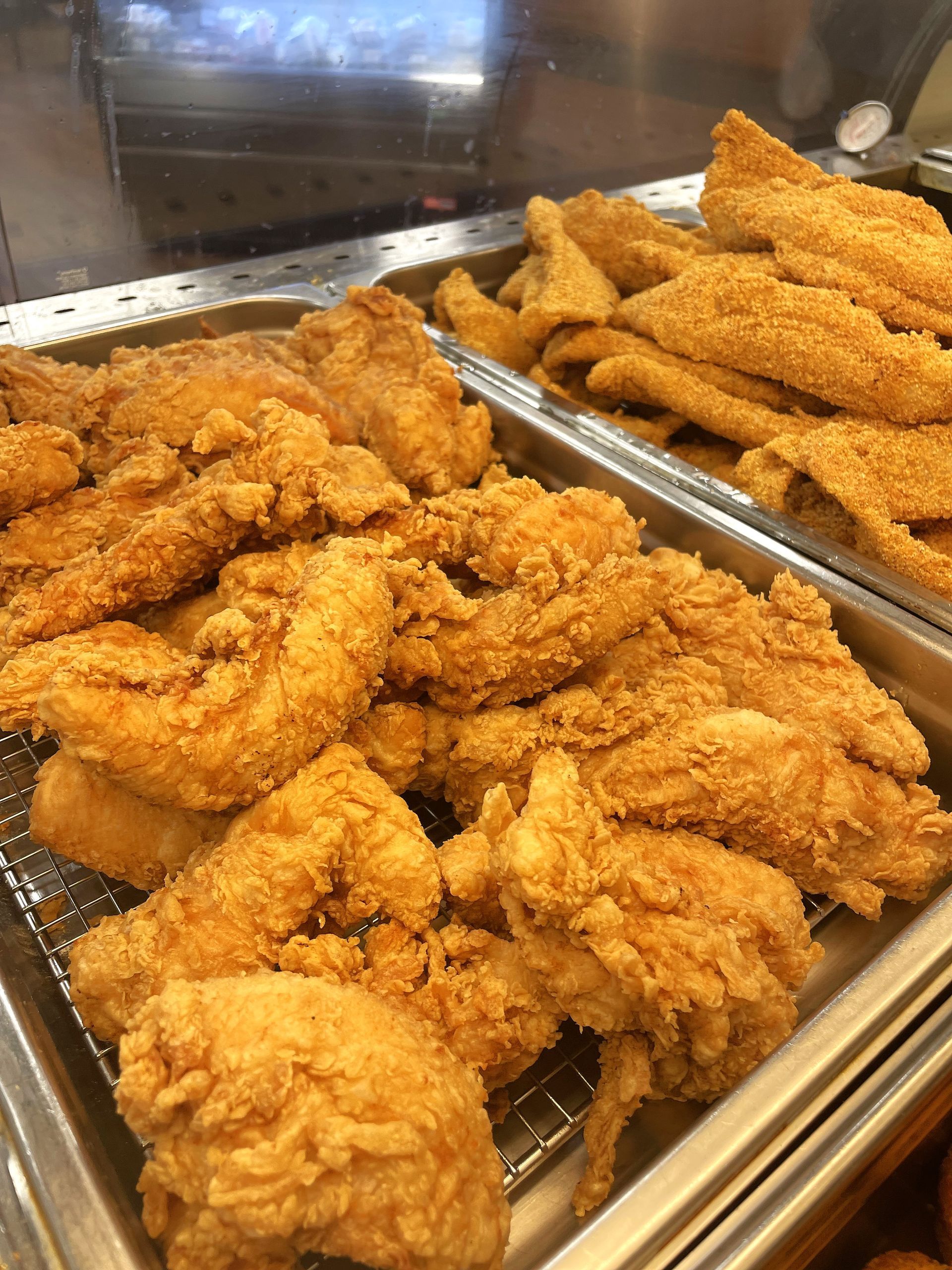 A tray of fried chicken and fish on a grill.