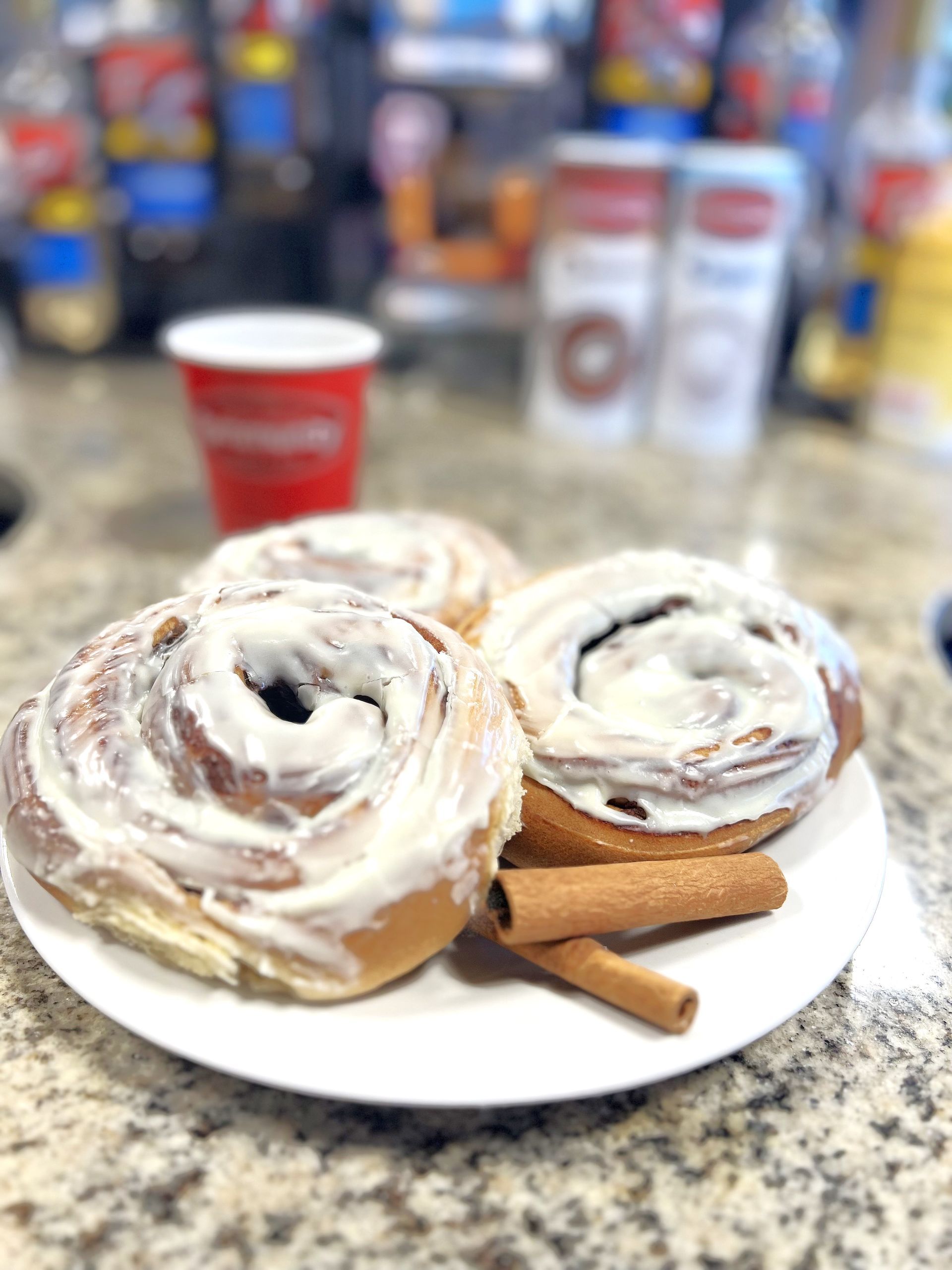 A white plate topped with cinnamon rolls and cinnamon sticks