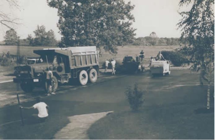 A black and white photo of a dump truck parked on the side of the road.