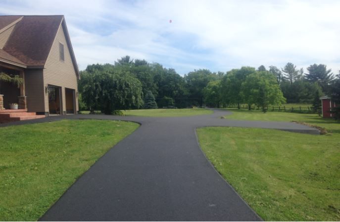 A driveway leading to a house with a lot of grass
