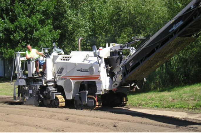 A man sits on a platform next to a machine that says ' wilson ' on it
